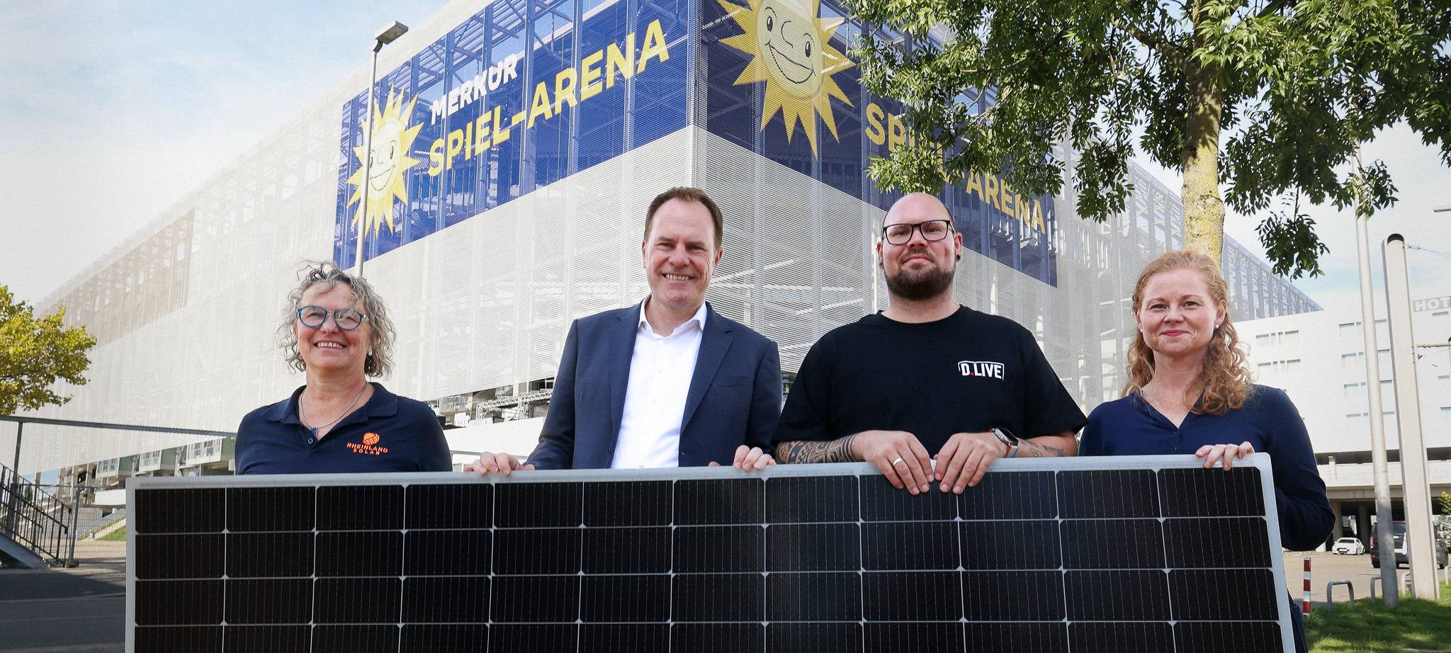 Oberbürgermeister Stephan Keller hält mit Verantwortlichen von D.LIVE ein Solar-Panel.