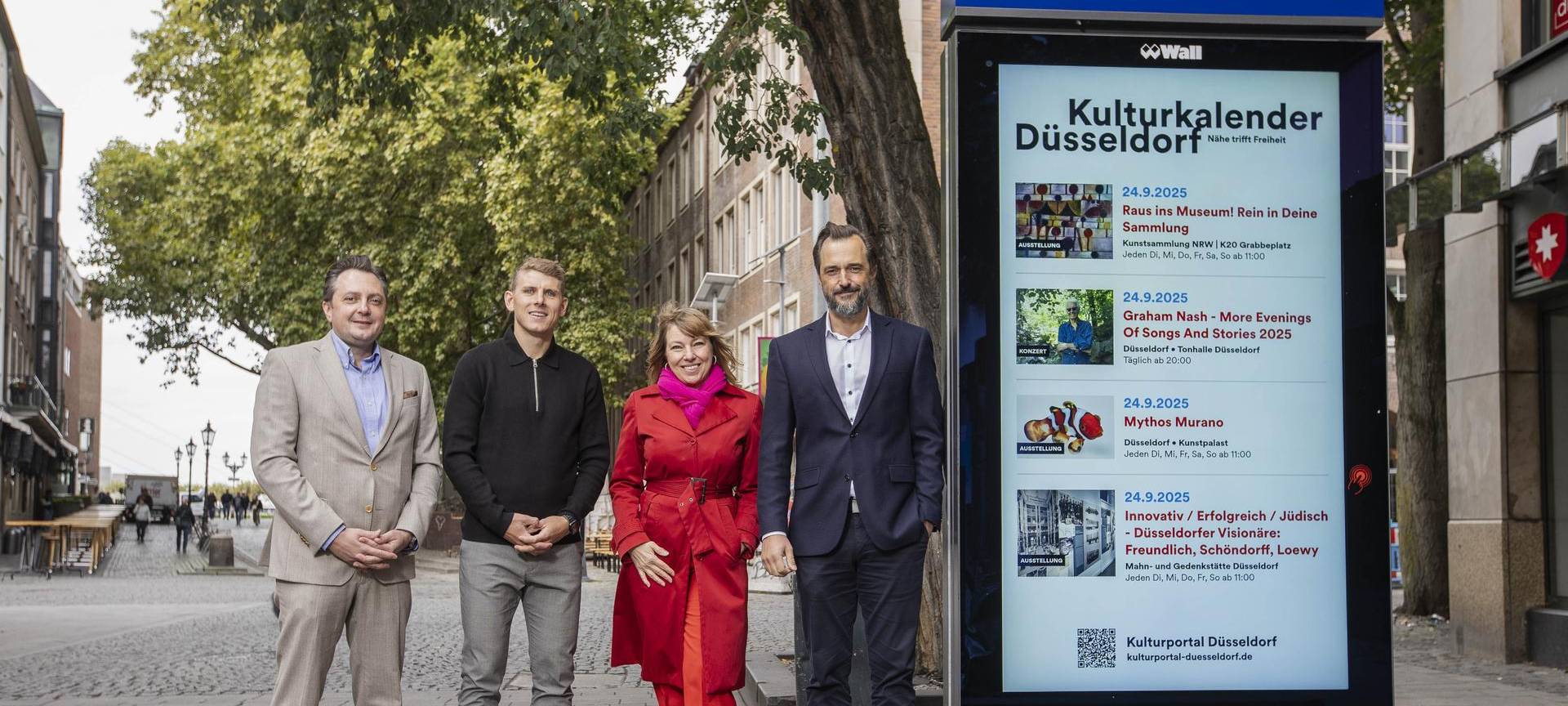 Vertretende von der Stadt neben der neuen Kultur-Infotafel auf der Bolkerstraße.