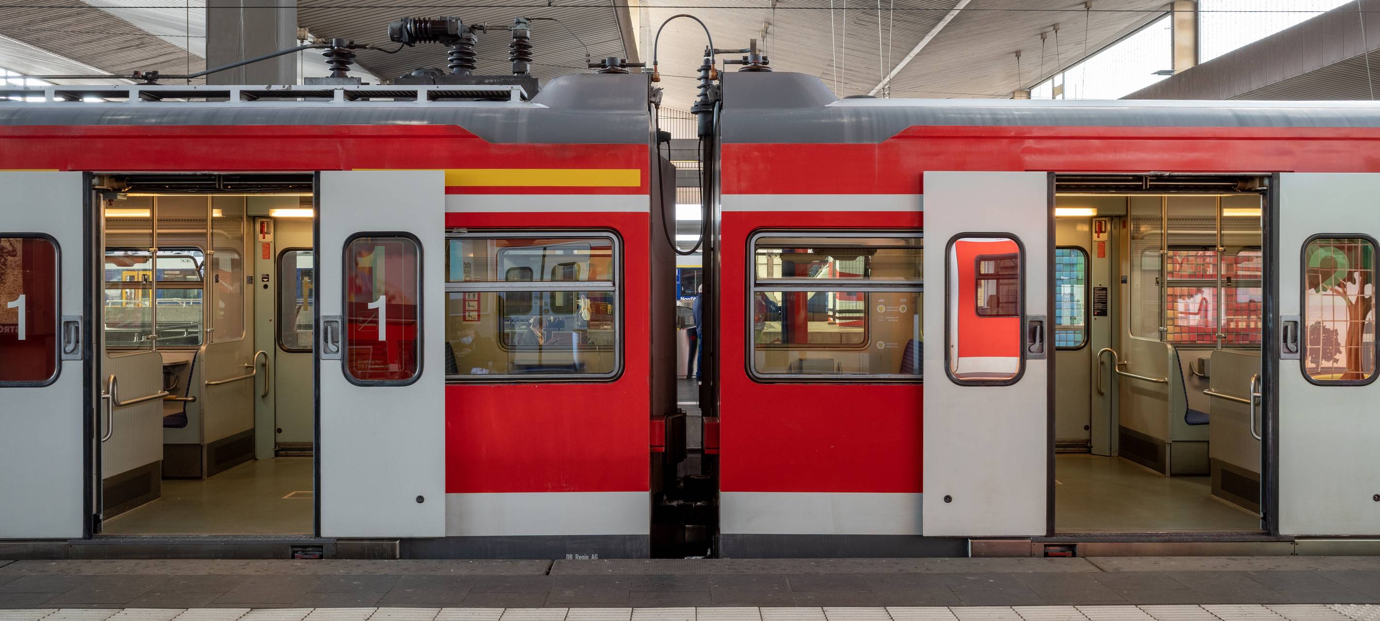 Eine S-Bahn hält am Bahnsteig eines Bahnhofs in Düsseldorf, Deutschland, und die automatischen Türen öffnen sich.