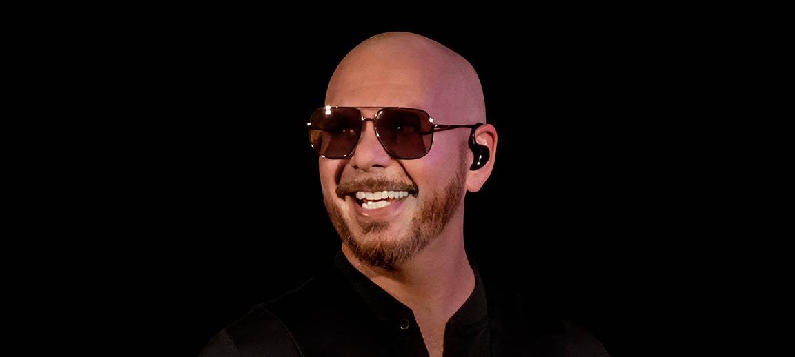 Der Künstler Pitbull steht vor einem schwarzen Hintergrund.