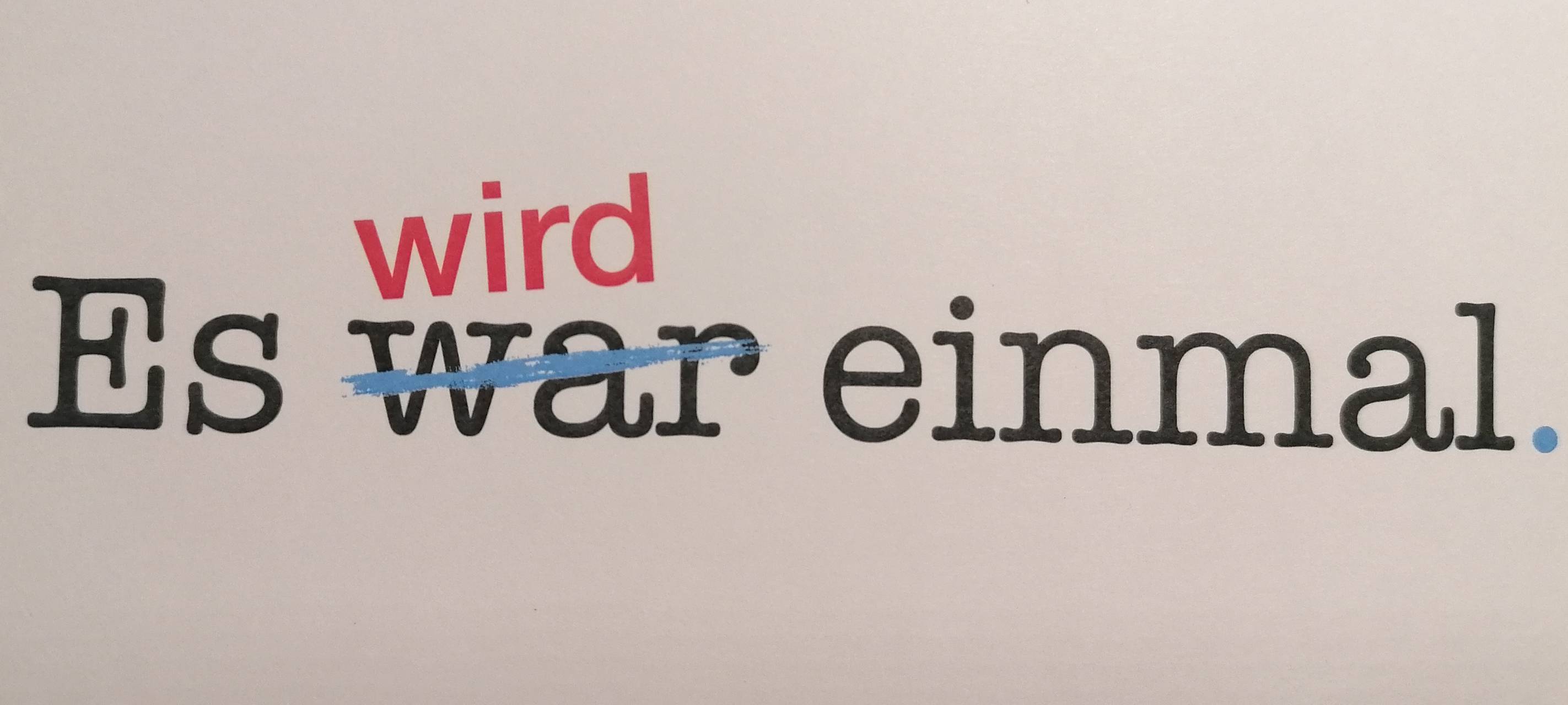 Schwarzer Schriftzug auf weißem Papier: "Es war einmal" - das "war" ist durchgestrichen. Darüber steht in roter Schrift "wird".