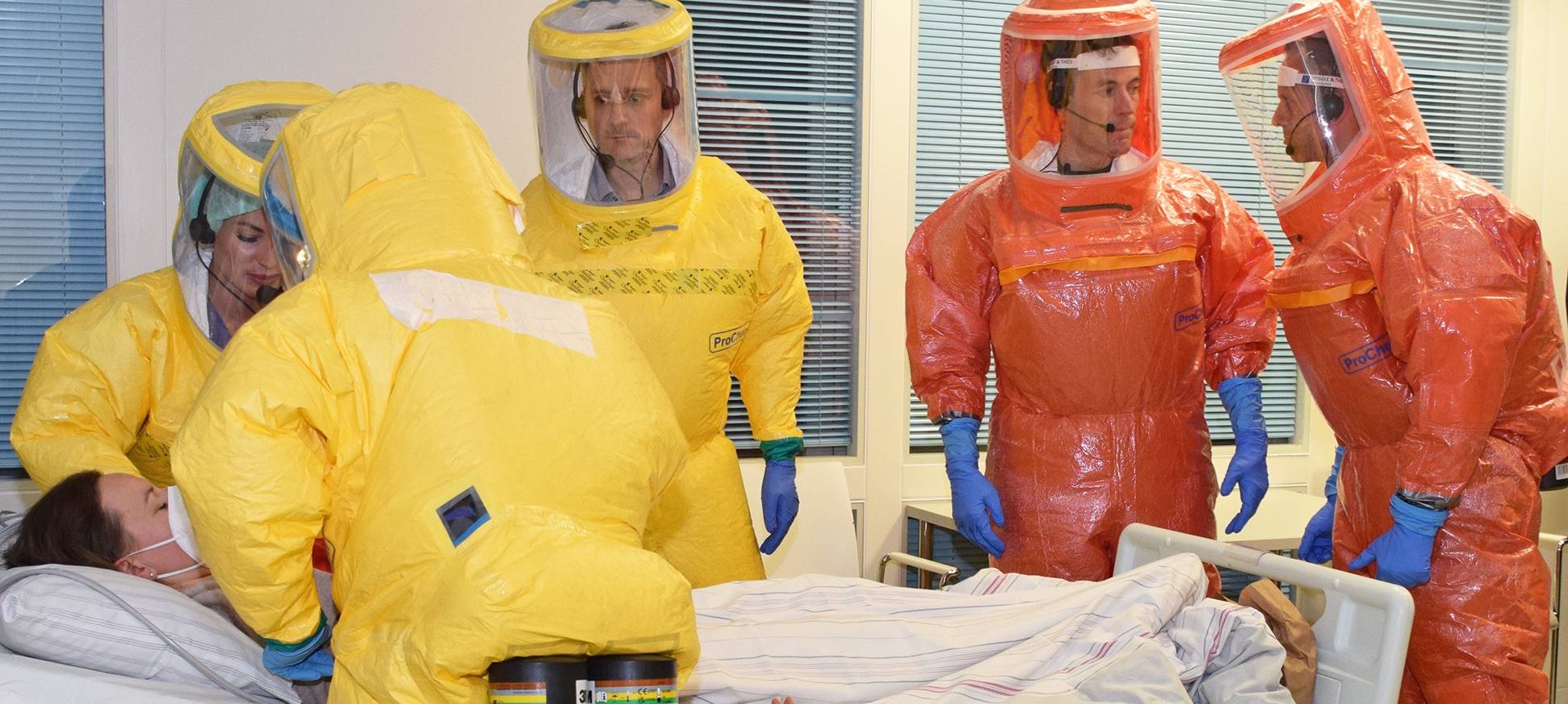 Retter in gelben und orangenen Schutzanzügen versorgen eine Patientin im Rahmen einer Hochinfektions-Übung.