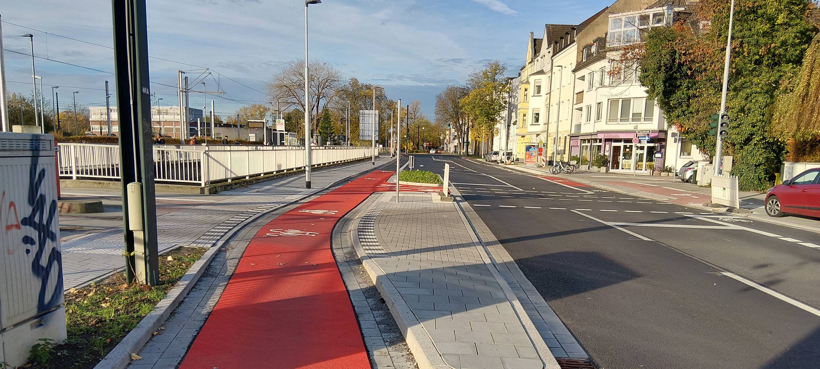 Neuer Radweg auf der Hildener Straße in Benrath. Er ist teilweise rot markiert. Links davon ist die Straßenbahntrasse zu erahnen, rechts sehen wir die Fahrbahn für Autos.