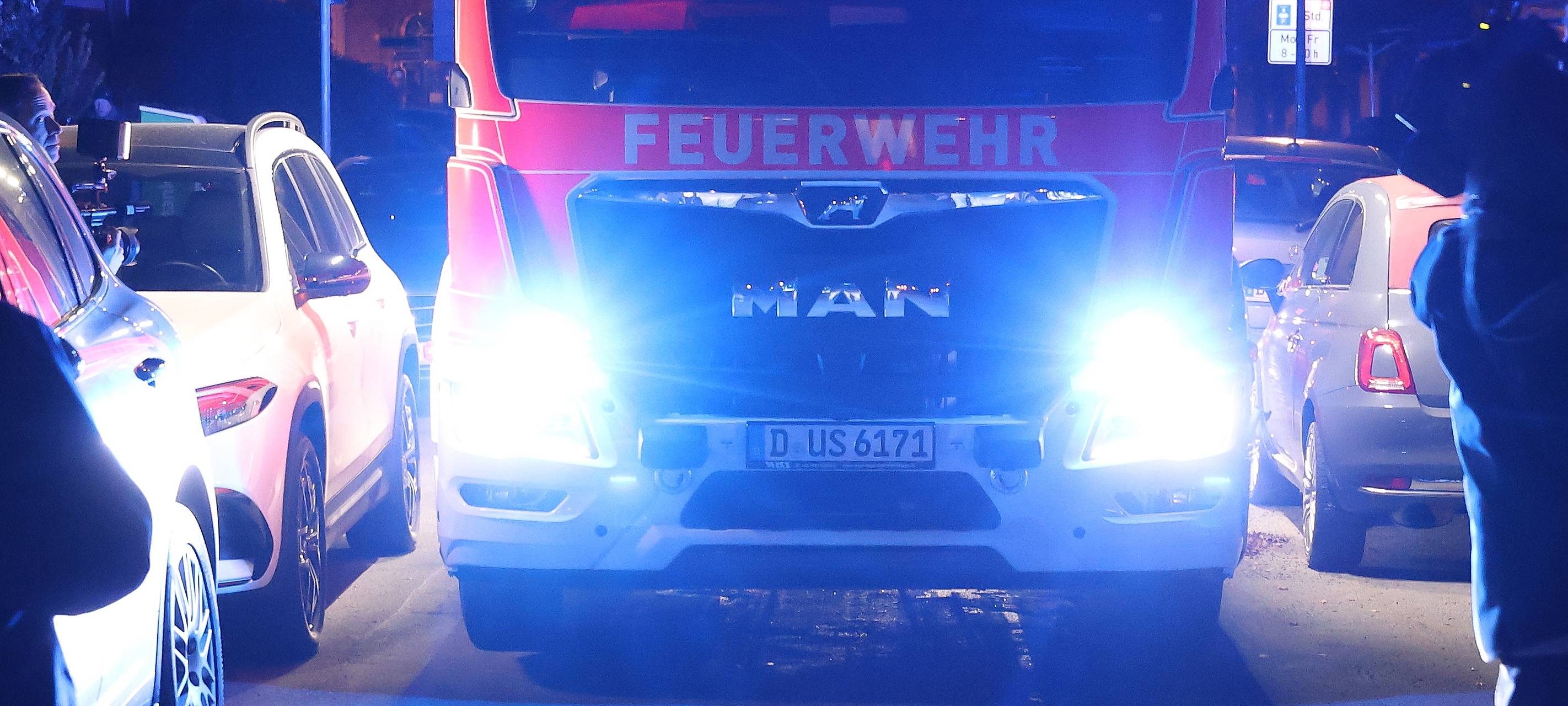 Ein Wagen der Feuerwehr hat Schwierigkeiten, durch eine eng geparkte Straße zu kommen.