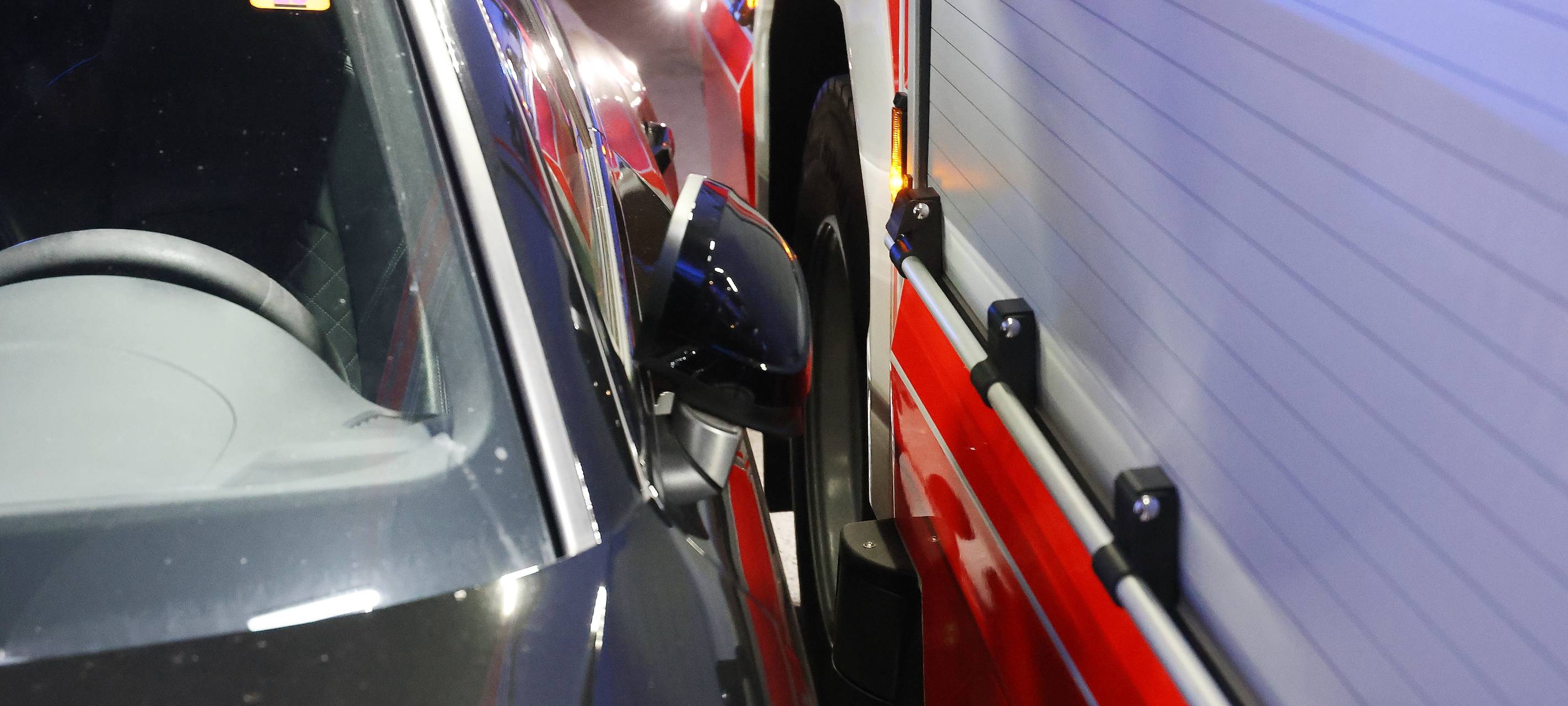 Ein Feuerwehrauto fährt nur mit knapper Not an einem geparkten Auto vorbei. Die Szene verdeutlicht, wie falsch oder eng geparkte Fahrzeuge Rettungskräften den Weg versperren und dadurch im Einsatz wertvolle Zeit verloren geht.