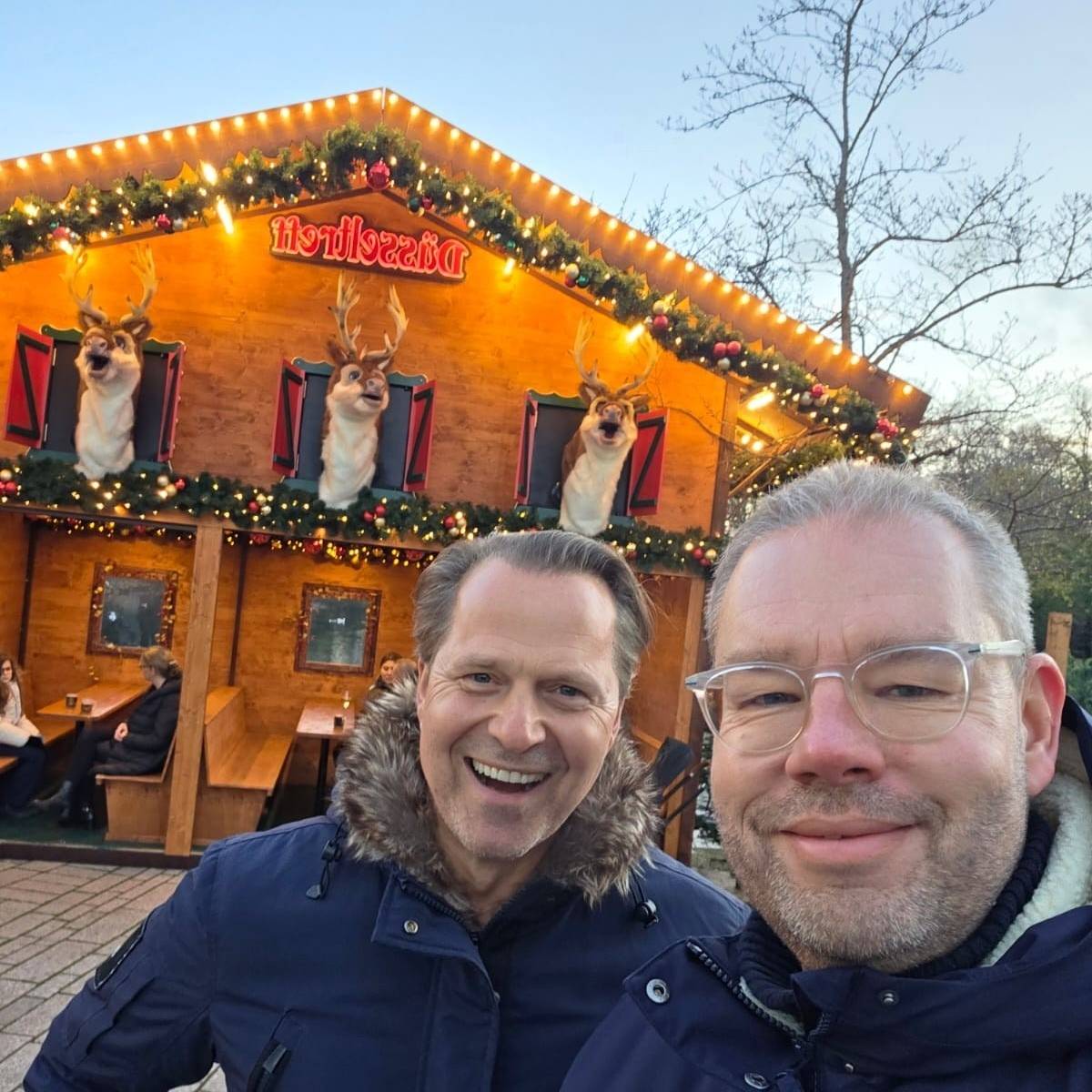 Antenne-Düsseldorf-Reporter Marc Pesch und Spitzenkoch Ernst Petry vor einer Bude auf dem Weihnachtsmarkt am Kö-Bogen.