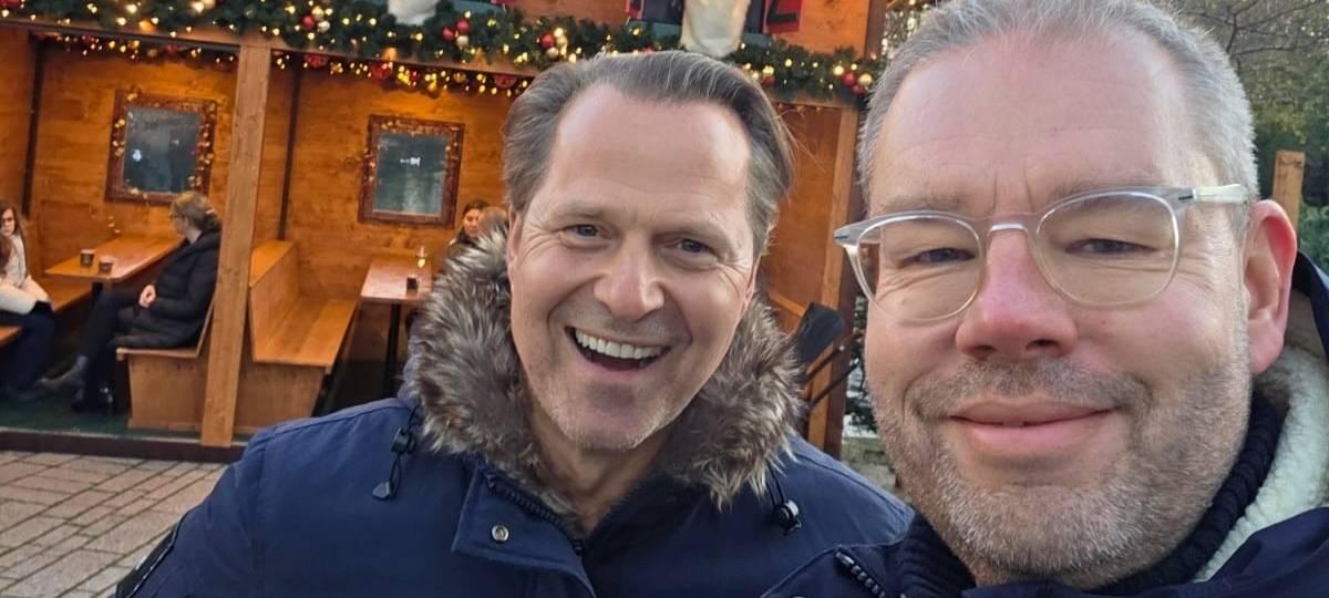 Antenne-Düsseldorf-Reporter Marc Pesch und Spitzenkoch Ernst Petry vor einer Bude auf dem Weihnachtsmarkt am Kö-Bogen.
