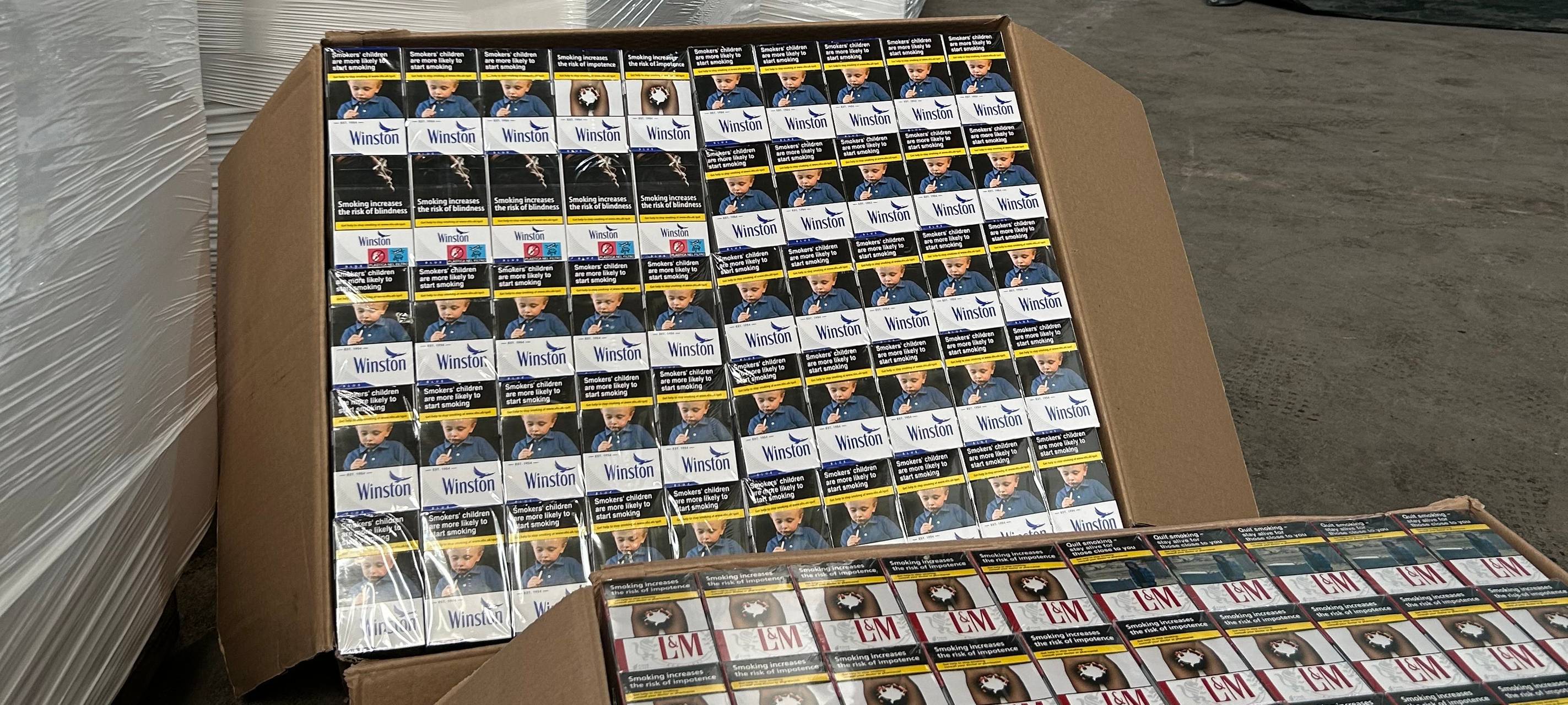 In einem Lager stehen mehrere große Kartons mit verschiedenen Zigarettenpackungen. Sie wurden bei Untersuchungen und Razzien gefunden.