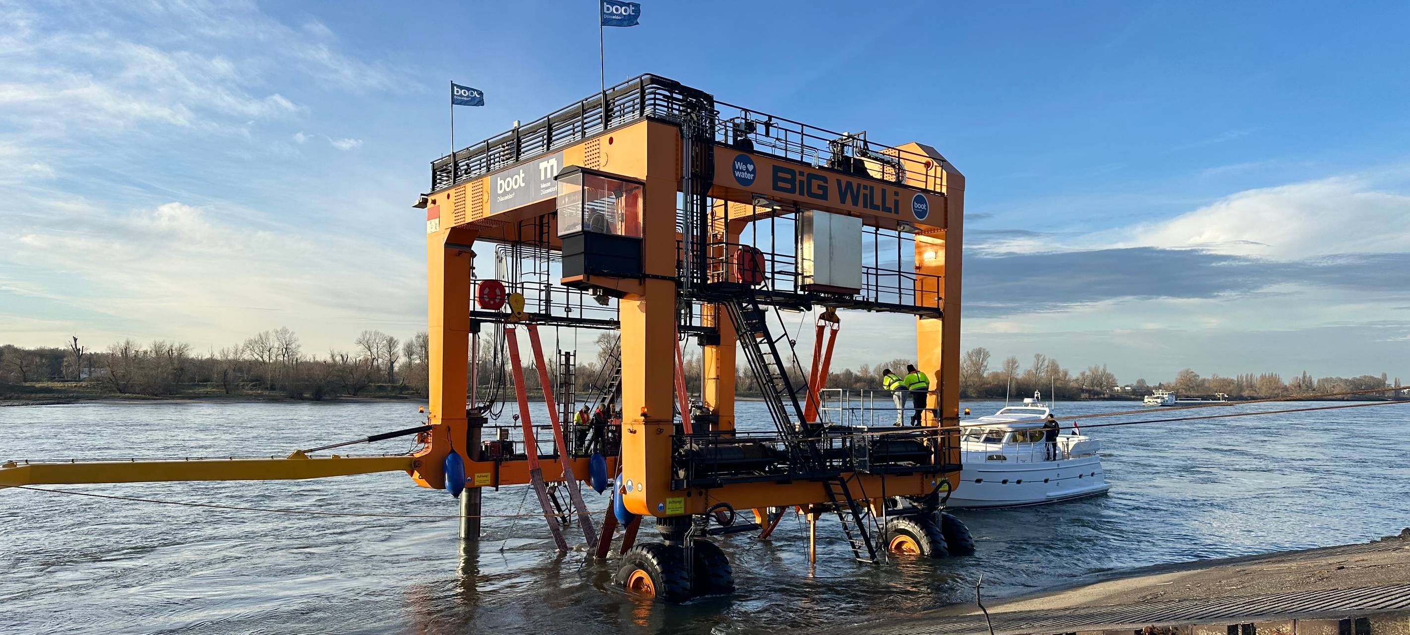 Der Messekran Big Will hebt eine Yacht für die Messe boot aus dem Rhein.