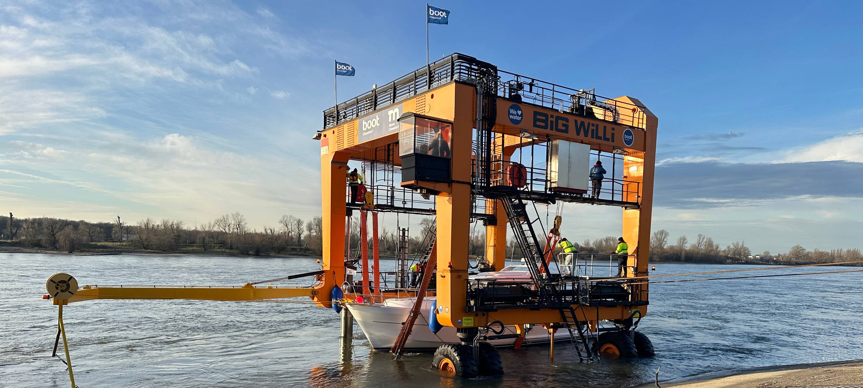Der Messekran Big Will hebt eine Yacht für die Messe boot aus dem Rhein.