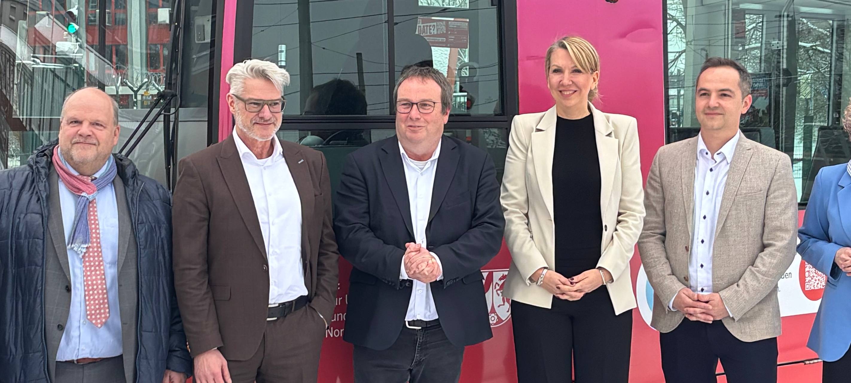 Umweltminister Krischer, Rheinbahn-Chefin Grabbe und weitere Personen stehen vor einer Rheinbahn, auf der "eezy.nrw" steht.
