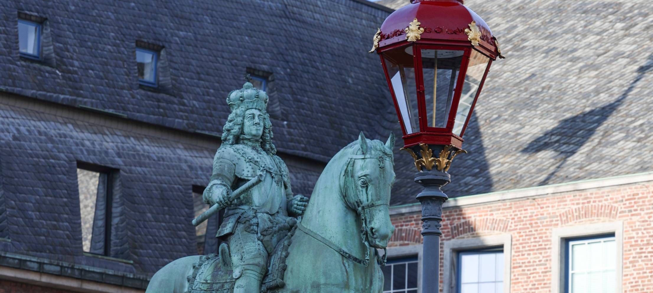 Neben dem Jan Wellem-Denkmal vor dem Düsseldorfer Rathaus steht eine rote, frisch renovierte LED-Leuchte.