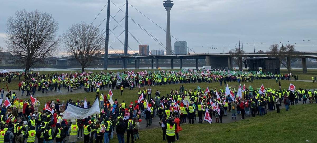 Menschen in Warnwesten sammeln sich am Rheinufer für einen Warnstreik der Gewerkschaft Verdi.