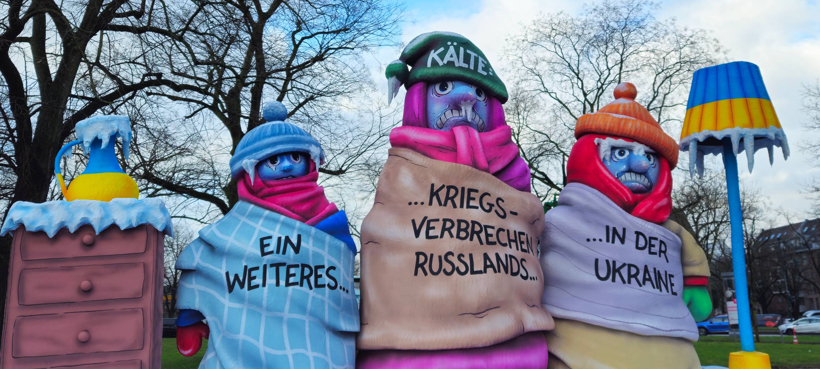 Drei Menschen frieren, und auf ihren Körpern steht: „Ein weiteres Kriegsverbrechen Russlands an der Ukraine.“