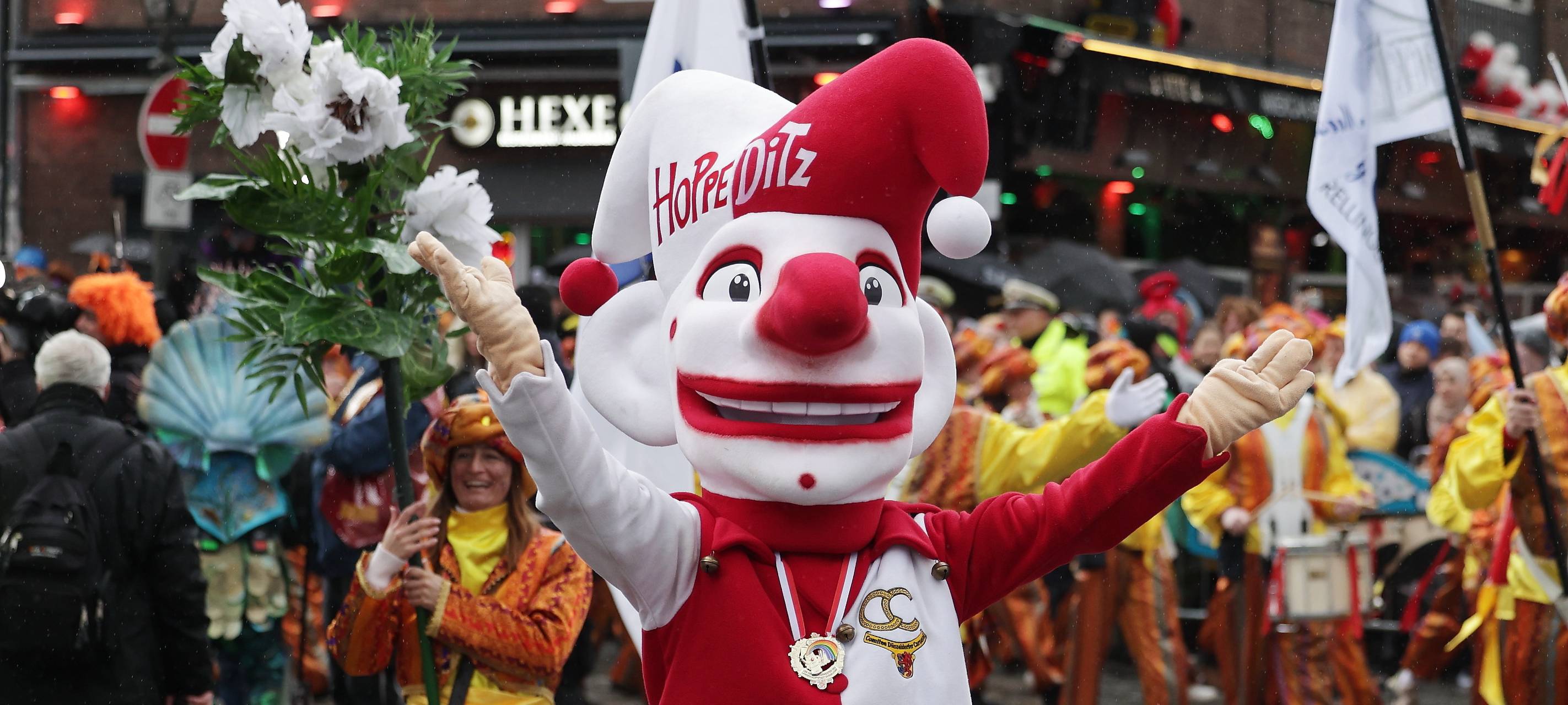 Der Hoppeditz läuft mit durch die Stadt beim Düsseldorfer Rosenmontagszug 2026. Im Hintergrund läuft eine Fußgruppe.