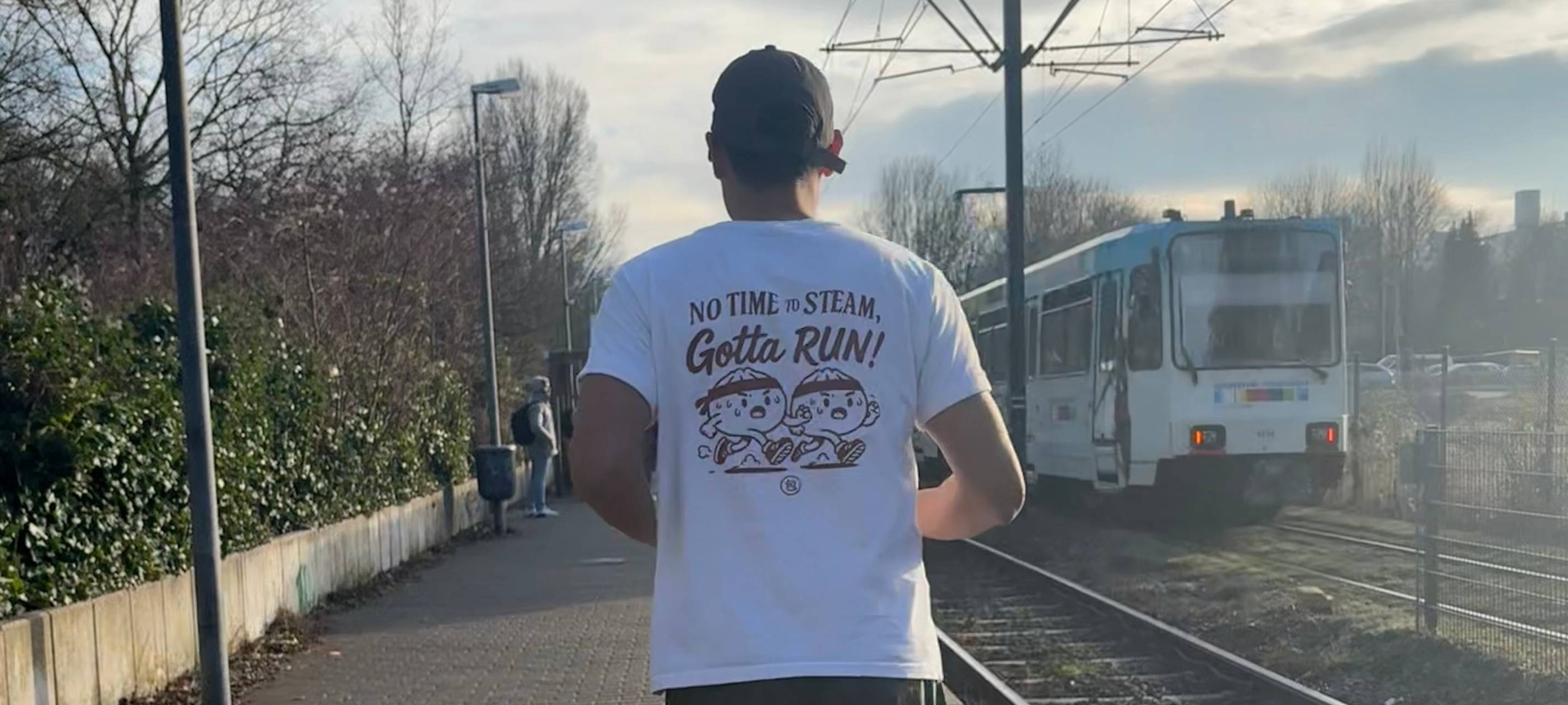 Oskar Cheong läuft an einem Bahnsteig entlang. Im Hintergrund fährt eine U-Bahn der Rheinbahn.