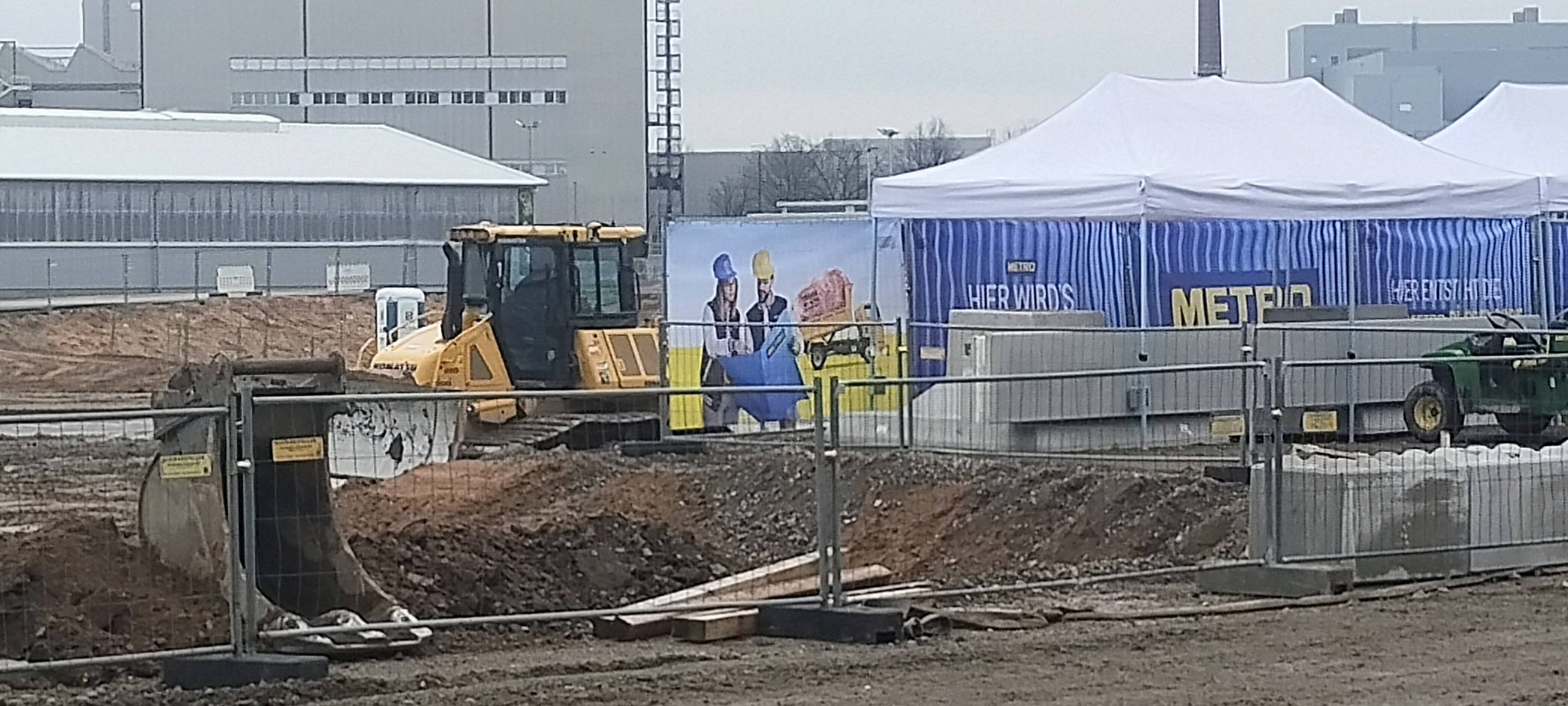 Große METRO-Baustelle an der Ulmenstraße mit Baggern und anderen schweren Geräten. Im Hintergrund weitere Hallen und ein Schornstein.