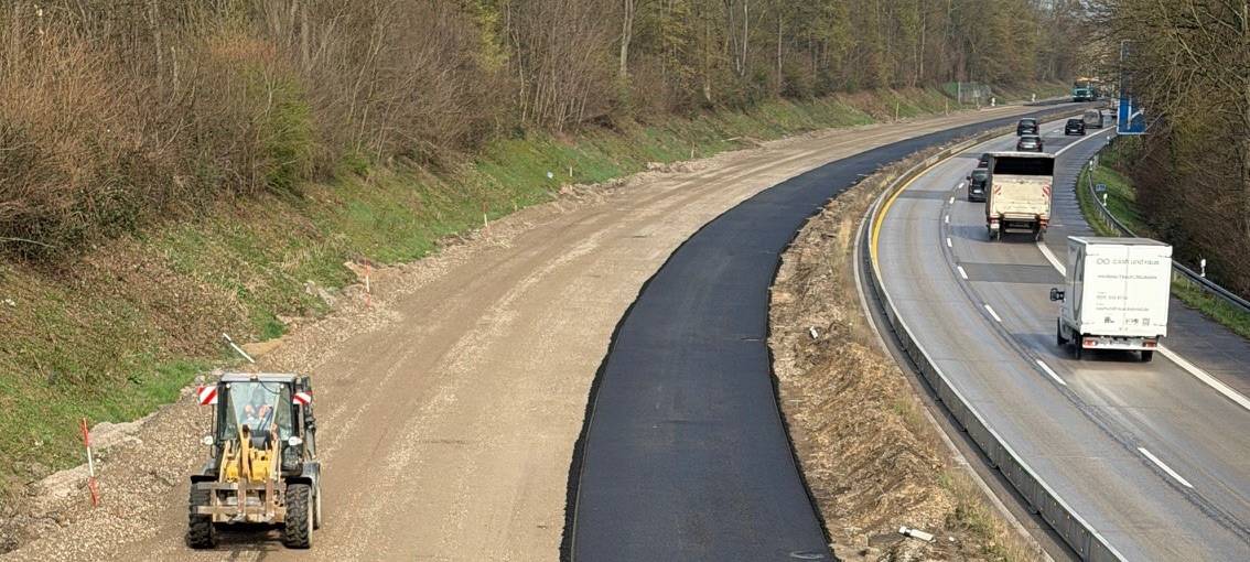Asphaltarbeiten auf der linken Fahrbahn A59-Baustelle. In Gegenrichtung fließt der Verkehr.