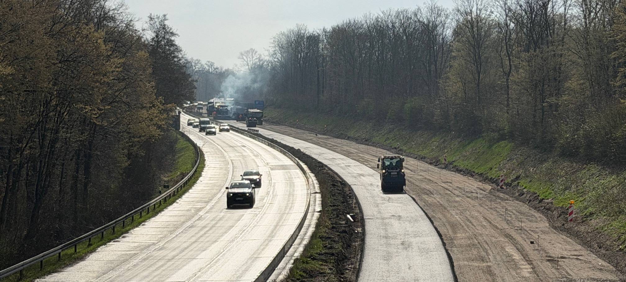 Asphaltarbeiten auf der linken Fahrbahn A59-Baustelle. In Gegenrichtung fließt der Verkehr.