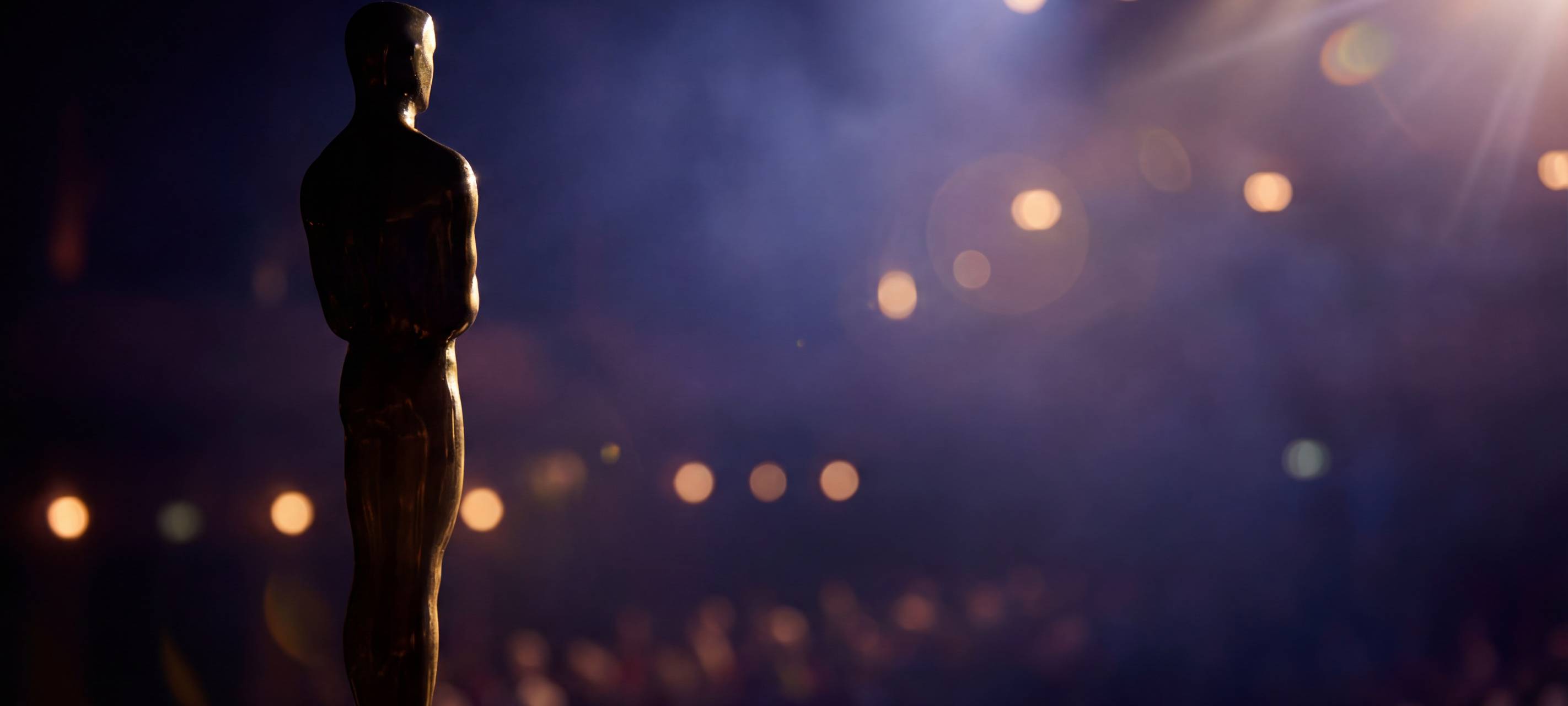 Goldene Trophäe auf einer Gala-Bühne. Dramatisches Spotlight mit Bokeh-Effekt zeigt die Silhouette der Trophäe bei einer Oscar-Verleihungsnacht. Die Trophäe steht als Symbol des Erfolgs für eine Zeremonie der Filmindustrie - ein Konzept der Award-Saison in Premium-Atmosphäre.