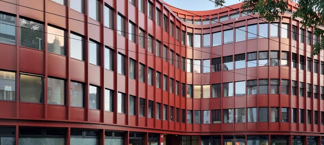 Die Verbraucherzentrale NRW in Düsseldorf: Ein geschwungenes, rotes Gebäude mit vielen Fenstern.