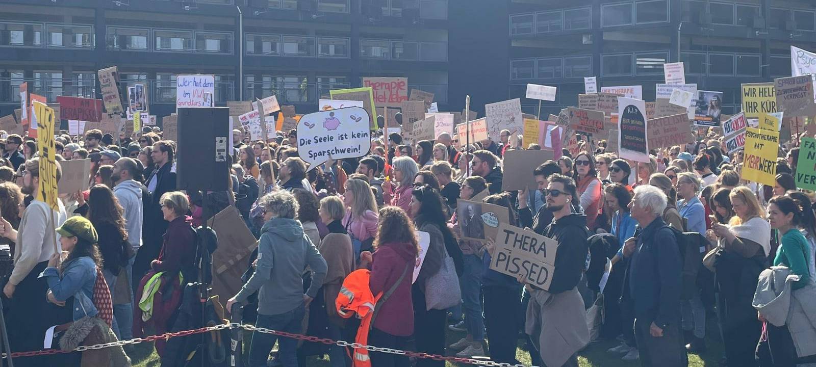 Menschenmenge mit Demo-Plakaten zum Thema Psychotherapie
