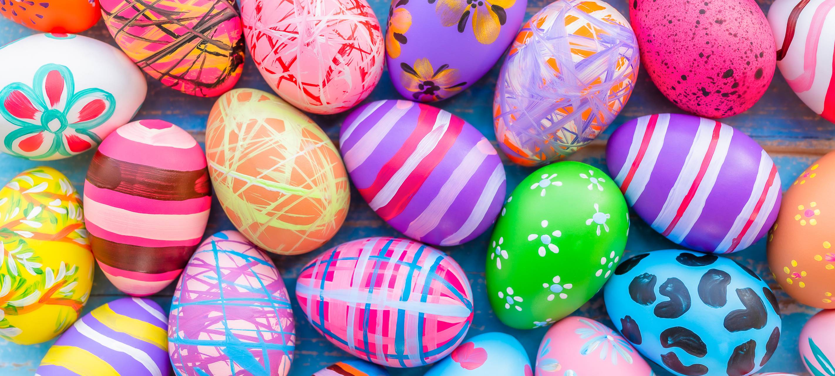 Bunte Ostereier auf einer blauen Holzunterlage.