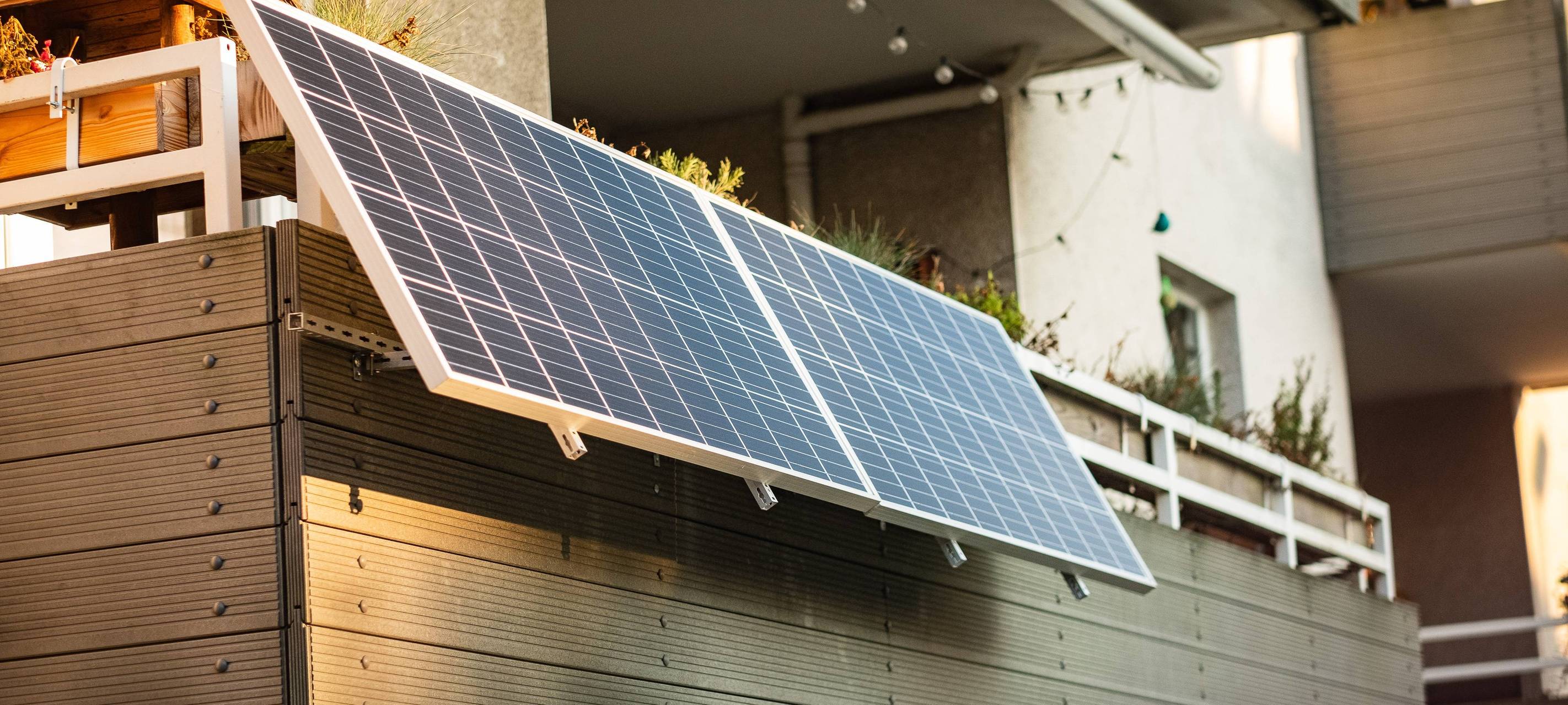 Zwei Solarpanels hängen an dem Zaun eines Balkons.