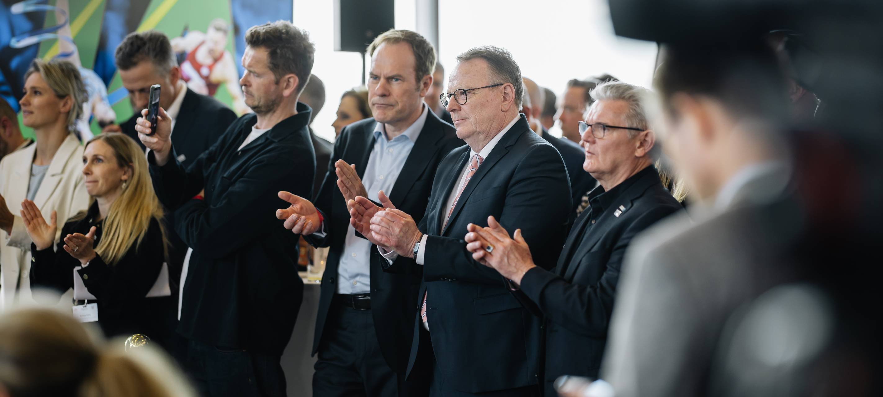 OB Keller steht bei der Veranstaltung zum Olympia-Bürgerentscheid in Köln inmitten von Amtskollegen und Verantwortlichen.