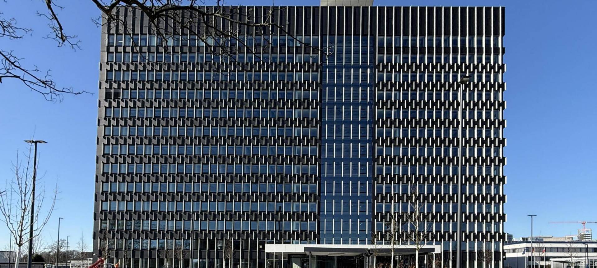 Frontansicht des neuen LKA-Gebäudes: Ein Hochhaus mir Glasfront und großem Eingang.