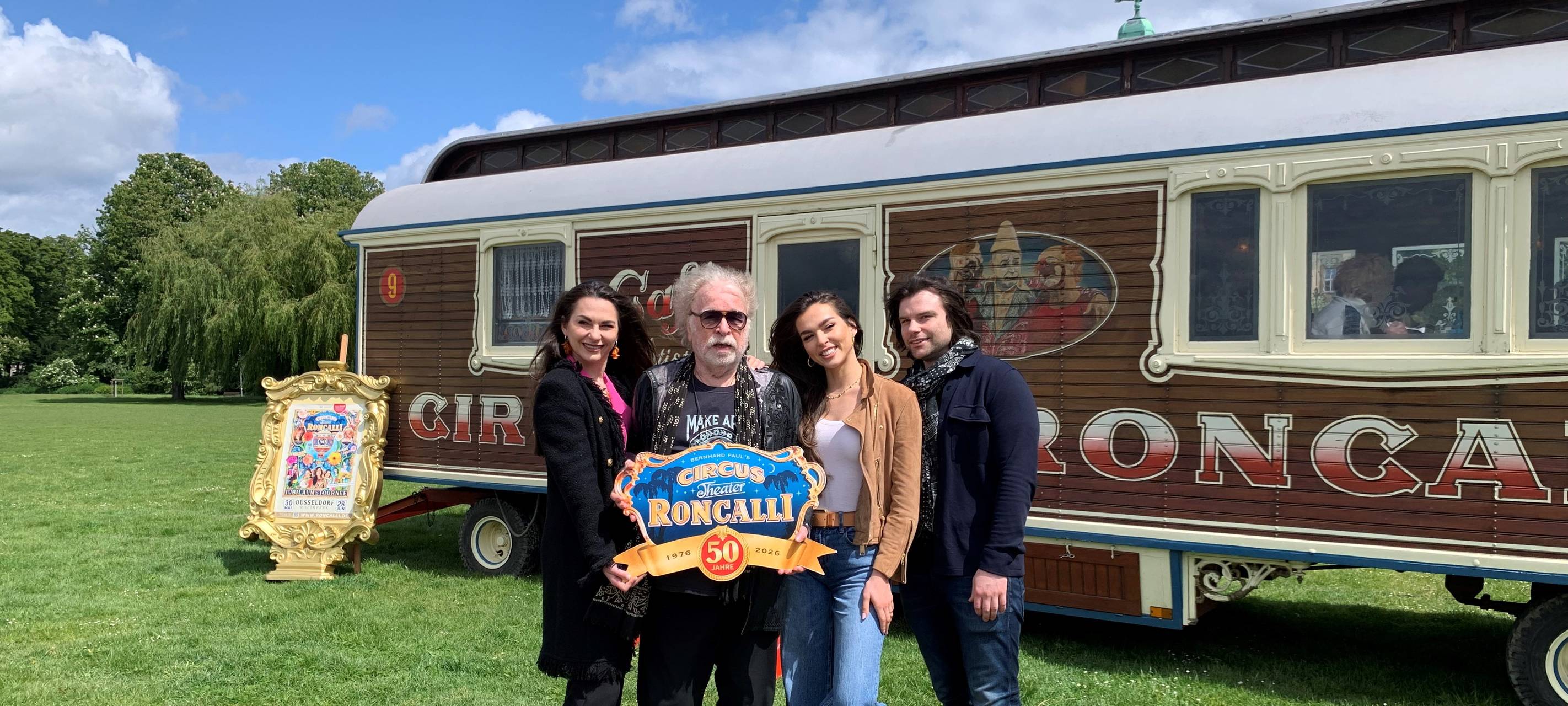 Apollo-Gründer Bernhard Paul und drei weitere Personen stehen vor einem Bauwagen des Circus.