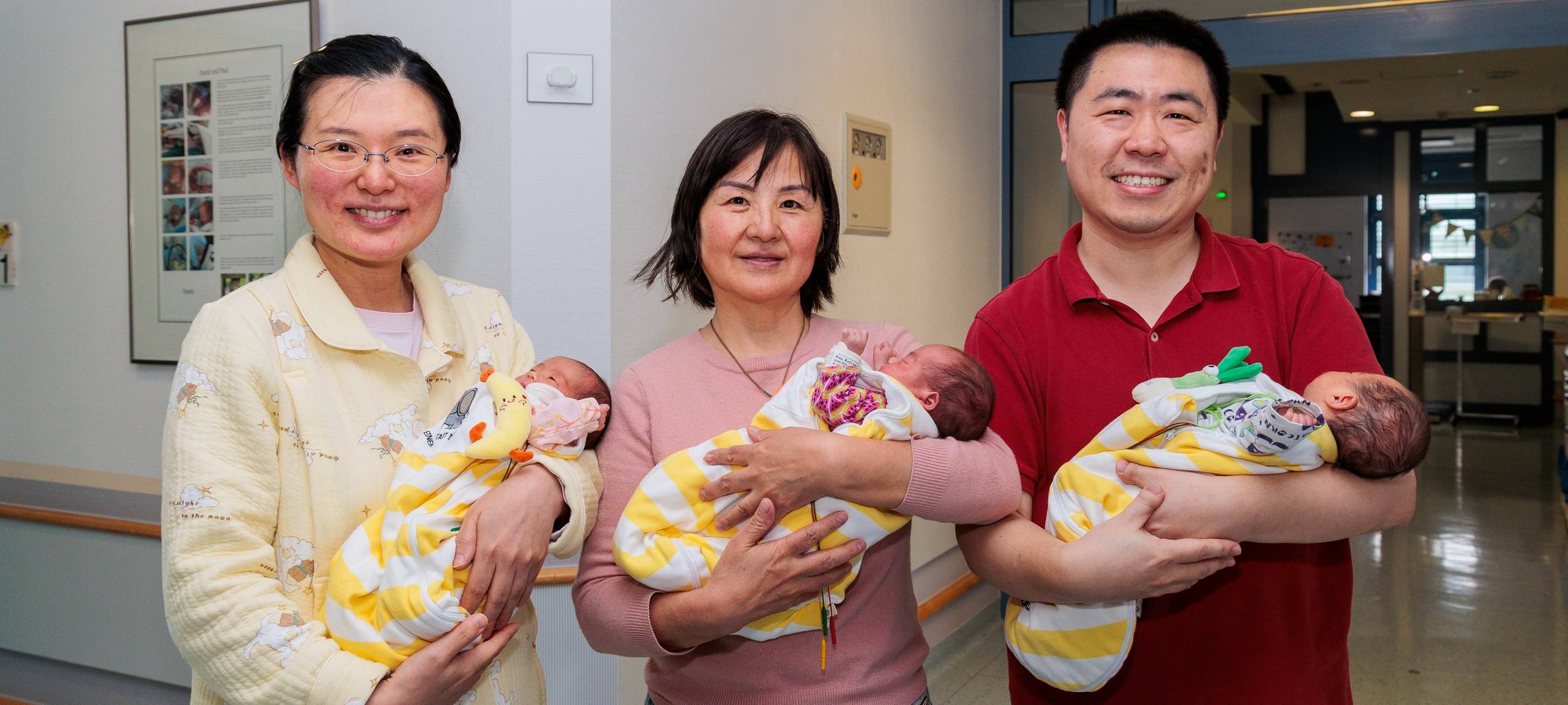 Eineiige Drillings-Mädchen Kexin Daisy, Keyi Amelia und Kerui Nora auf dem Arm von Mutter Dan Wang, der Großmutter und dem Vater Kai Wan