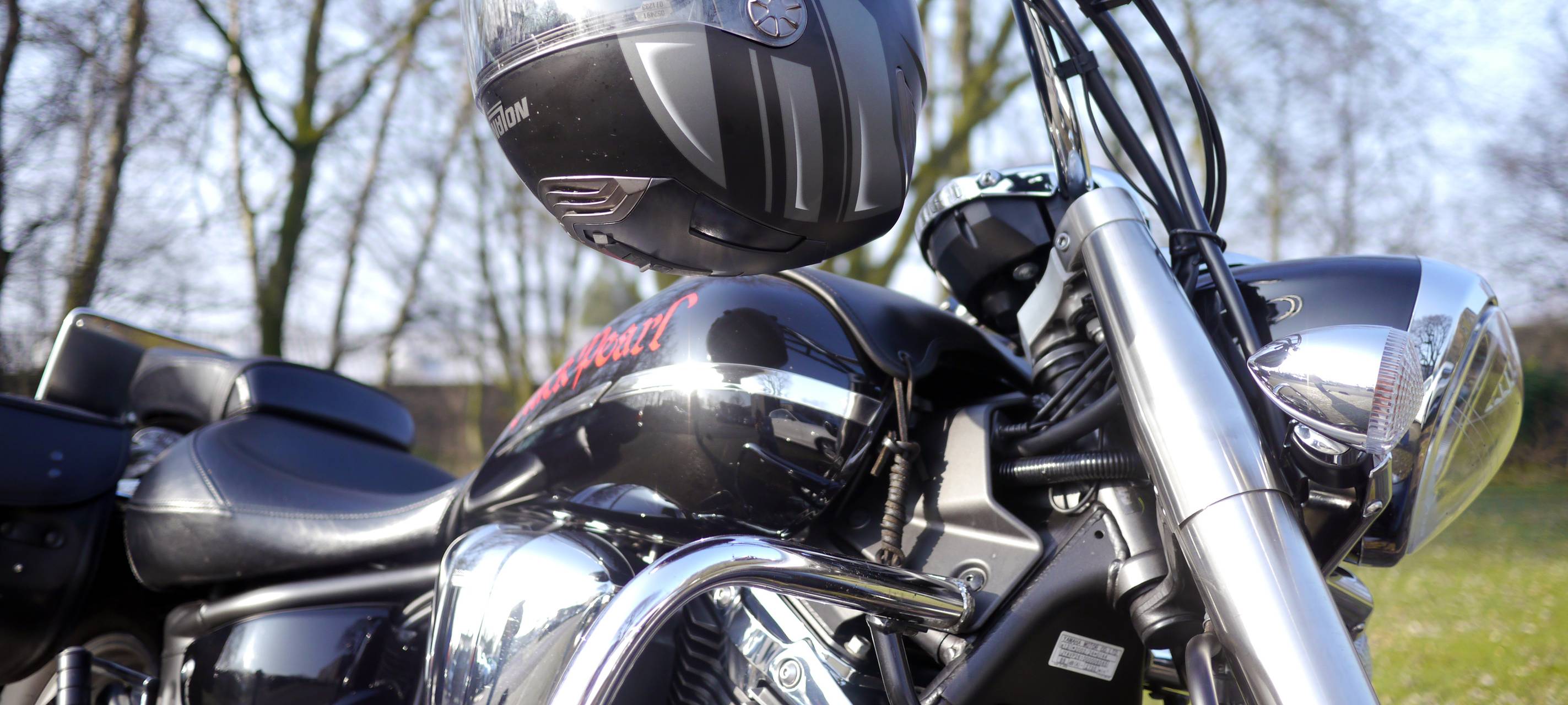 Nahaufnahme eines Motorrads in klassischer Optik und eines Motorradhelms am Lenker