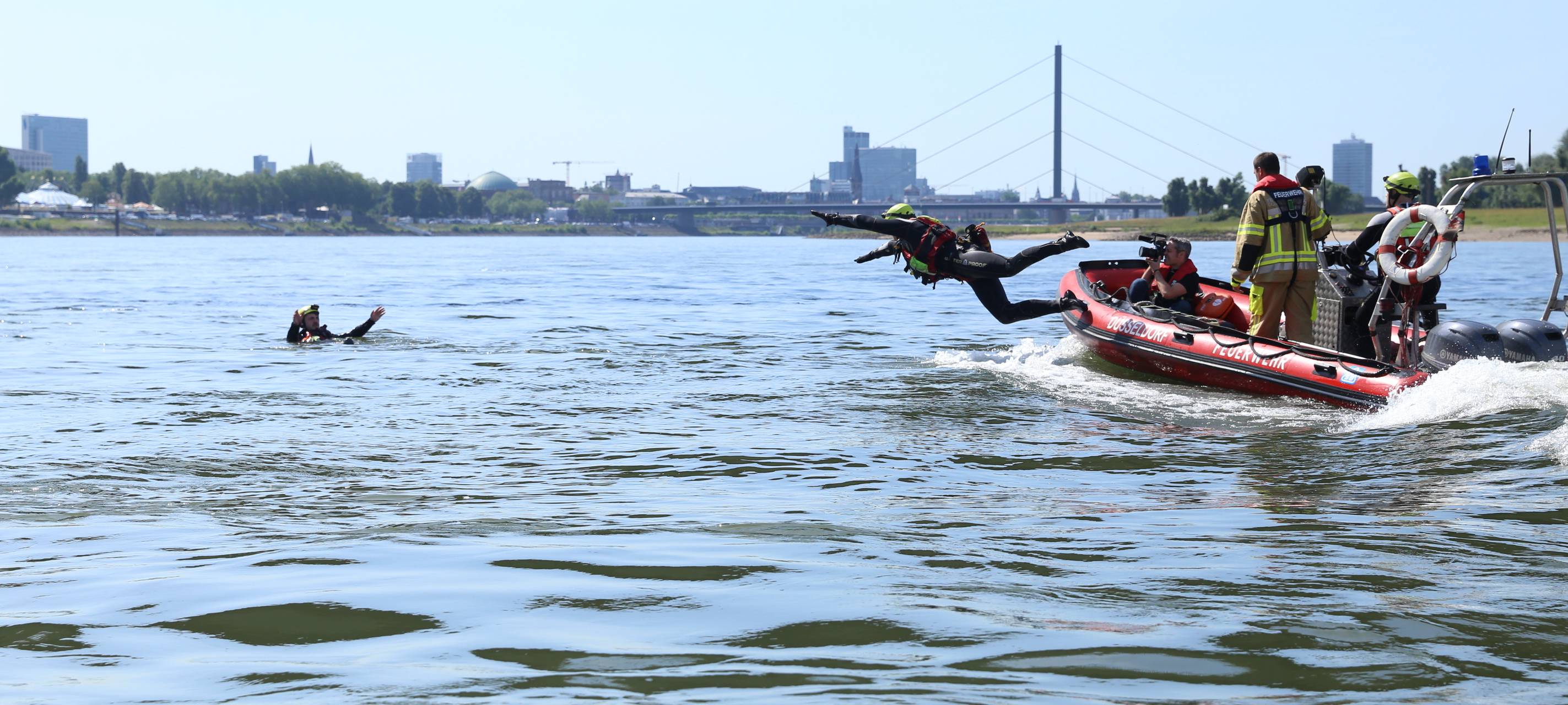 Die Düsseldorfer Feuerwehr übt die Rettung einer Person aus dem Rhein. Ein Helfer springt vom Rettungsboot aus ins Wasser.