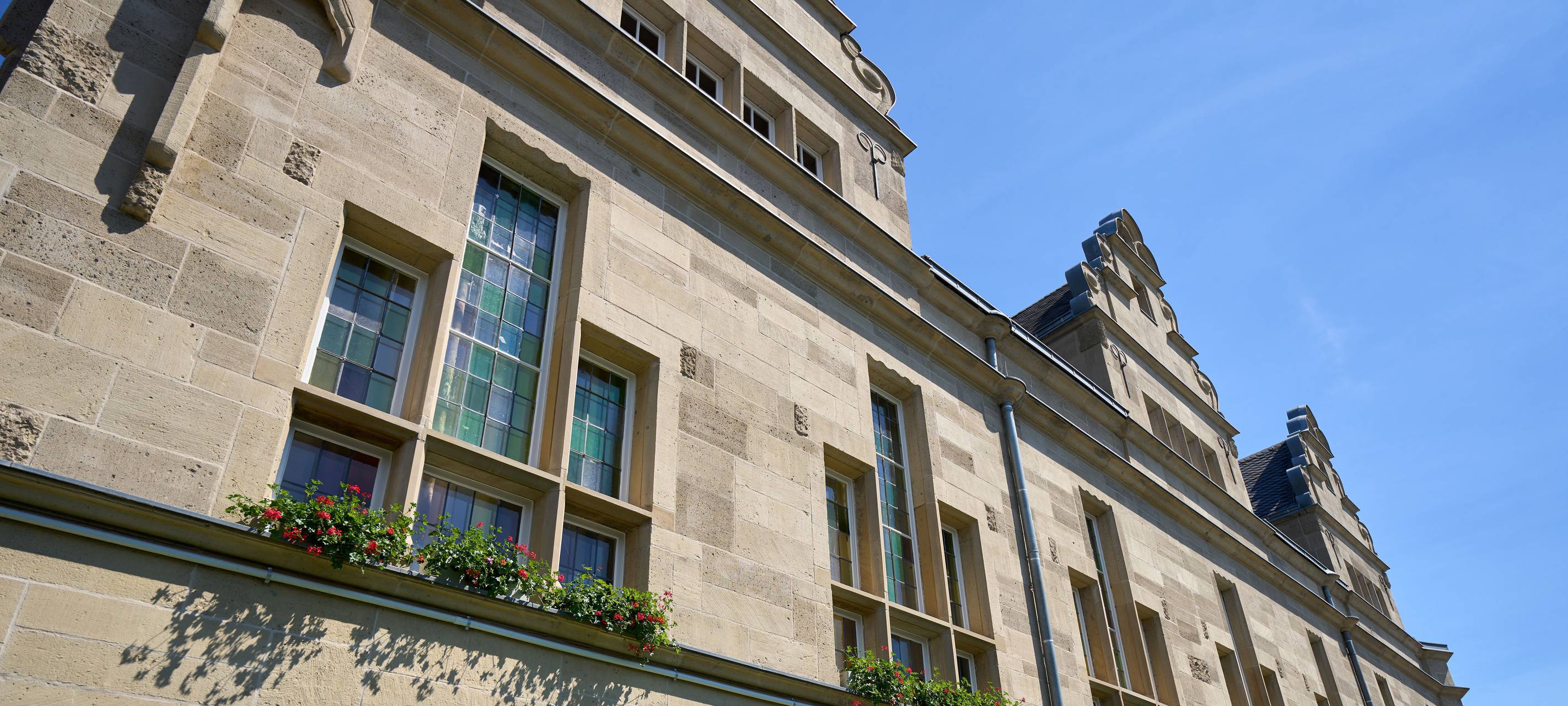 Die erneuerte Fassade des sanierten Benrather Rathauses. Die Fenster sind von außen mit einigen Blumen geschmückt.