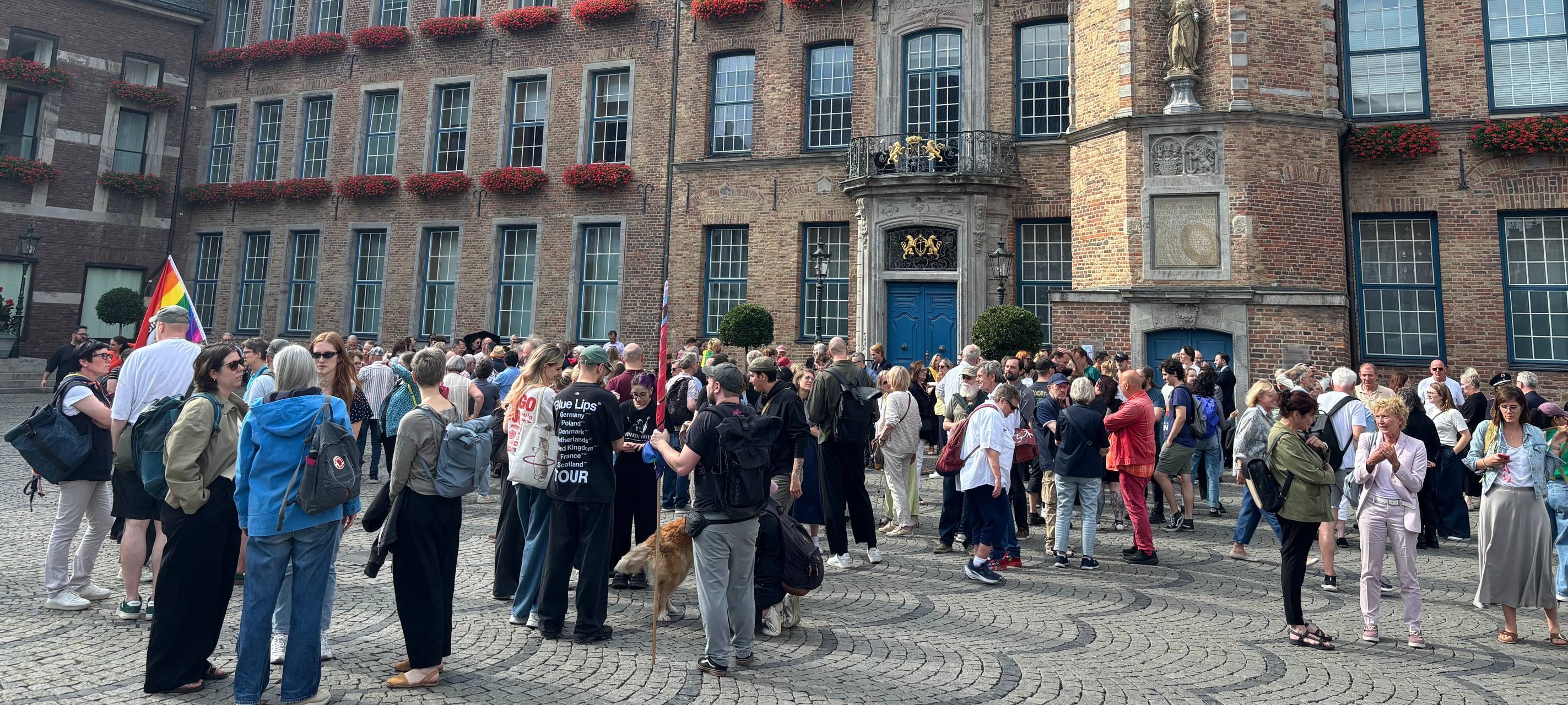 Menschen versammeln sich für eine Schweigeminute vor dem Rathaus.