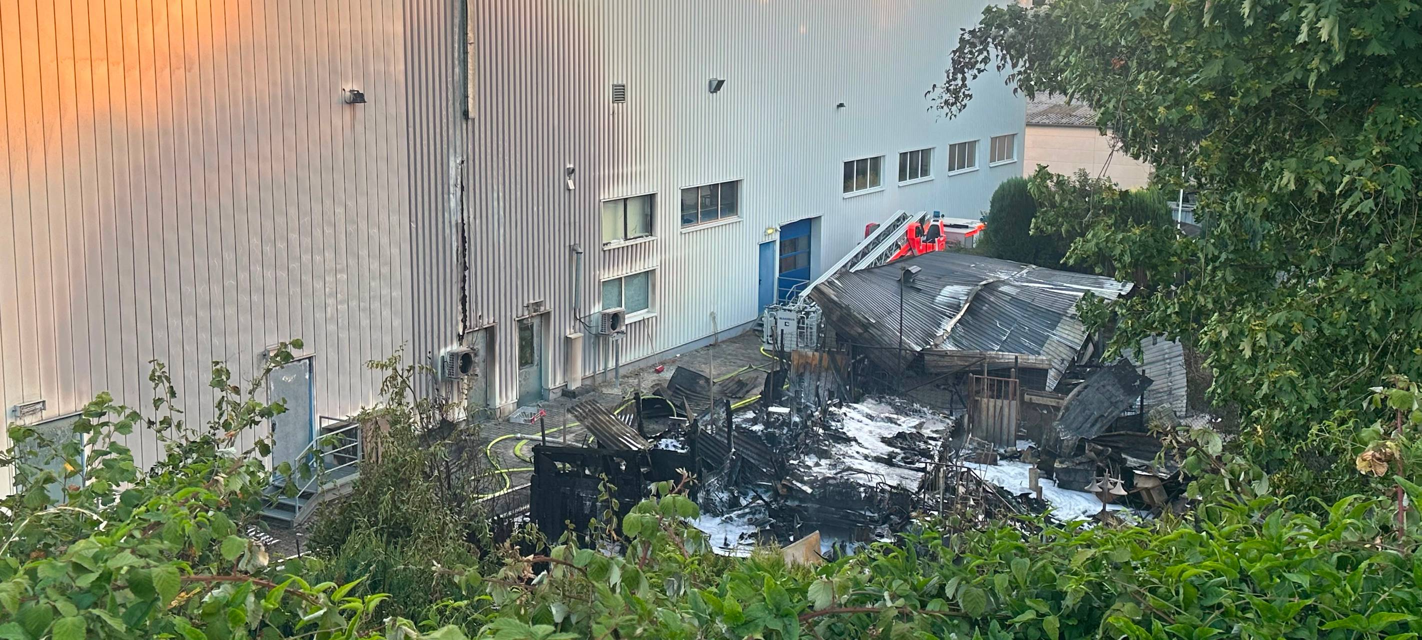 Abgebrannte Gartenlaube neben Industriehalle