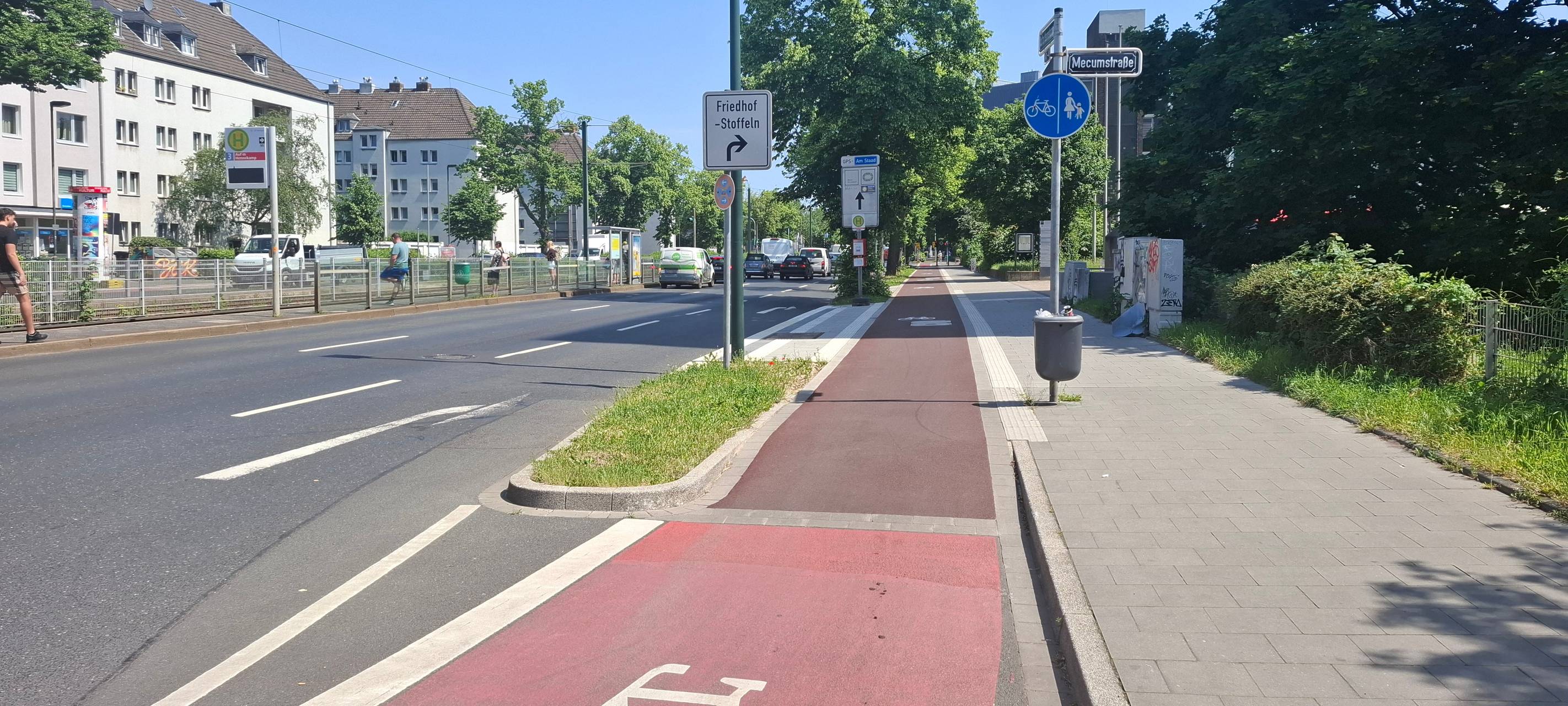 Gesonderter roter Radweg neben den Autospuren "Auf´ m Hennekamp". Zu Beginn des Radwegs ist ein weißes Fahrrad-Piktogramm aufgemalt.