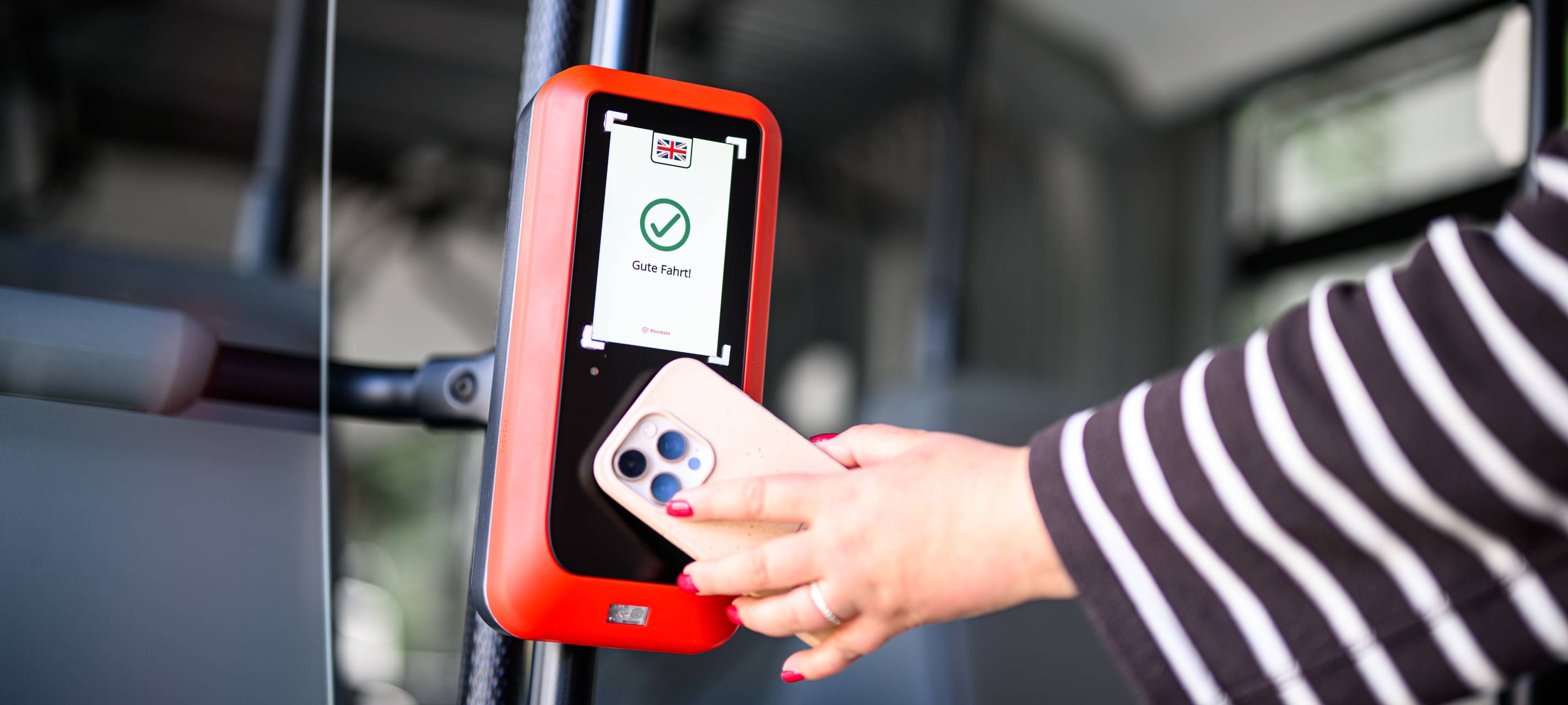 Eine Rheinbahnkundin hält ihr Handy vor ein neues CALO-Lesegerät.