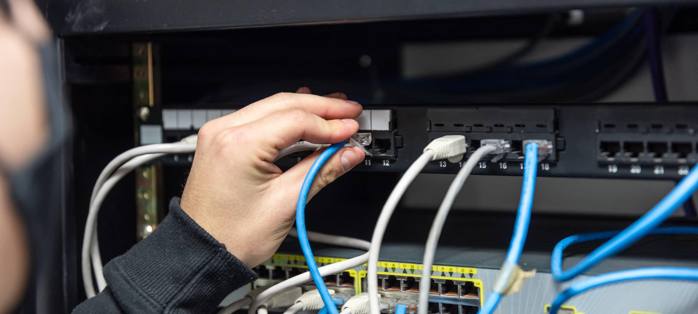 IT-Techniker verkabelt Server-Rack - wie in Düsseldorfer Rechenzentren, die das Stromnetz belasten.