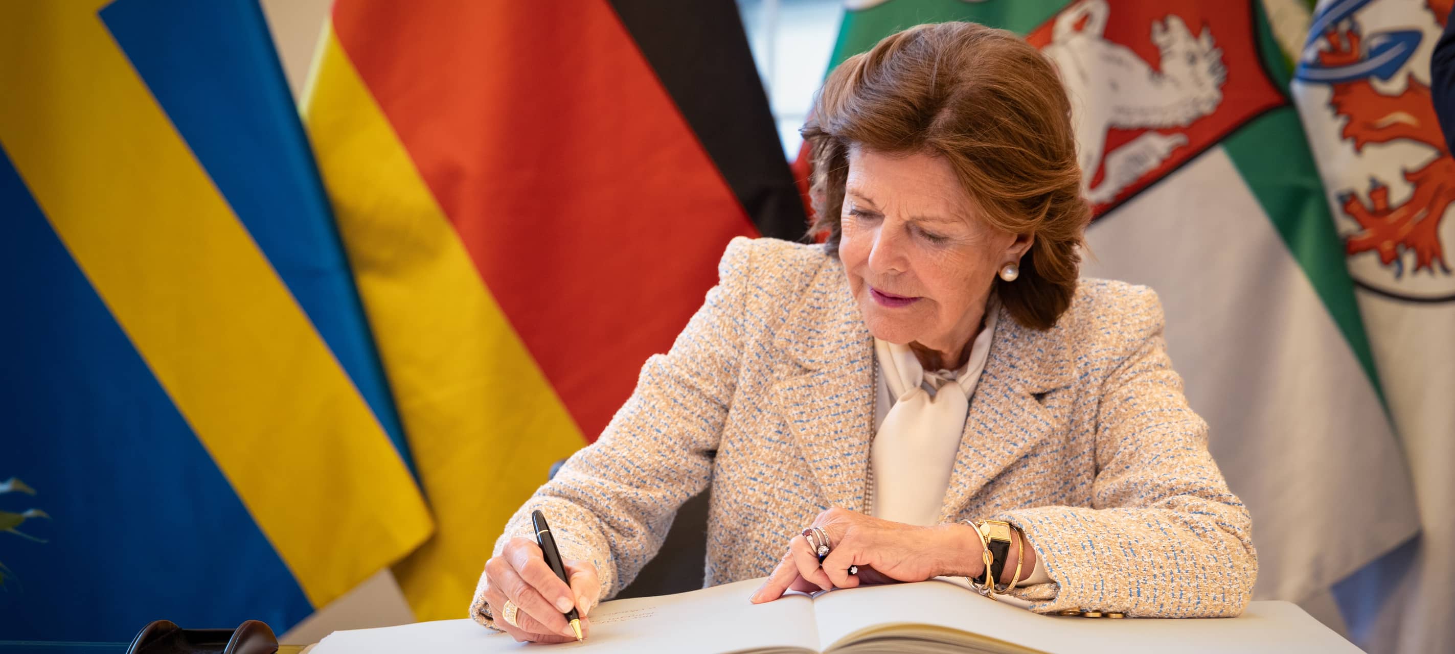 Königin Silvia von Schweden unterschreibt im goldenen Buch der Stadt.