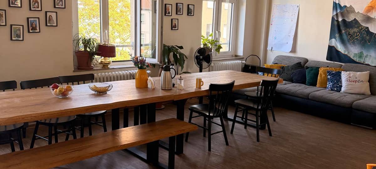 Aufenthaltsraum I in der SleepIn Notschlafstelle mit großem Esstisch und Sofa