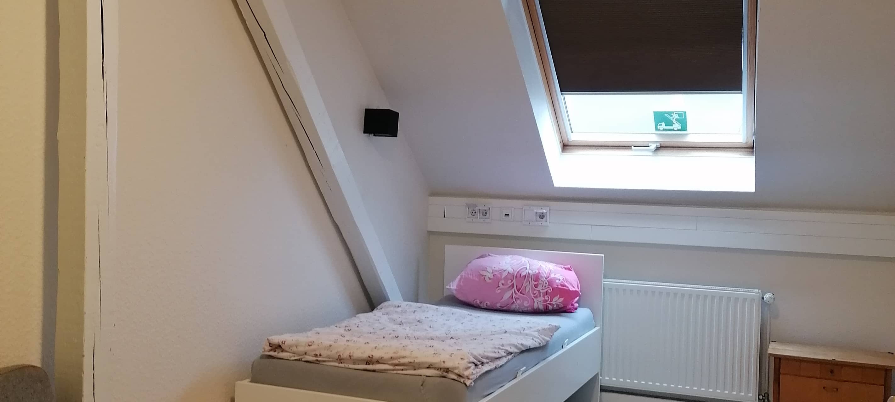 Schalfzimmer in der SleepIn Notschlafstelle mit Stuhl, Bett und Nachttisch