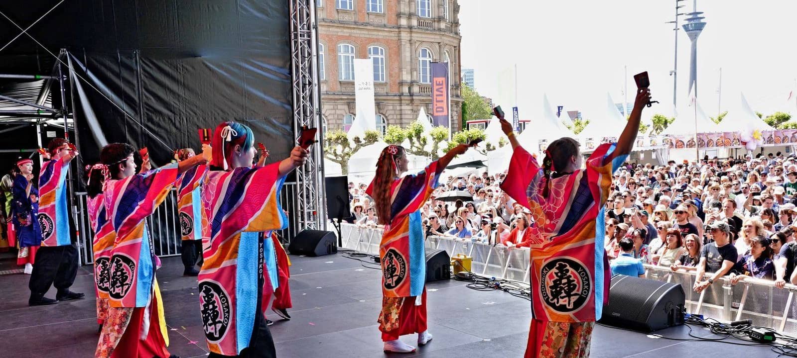 Japanische Künstlerinnen und Künstler auf der Bühne am Burgplatz. Im Hintergrund ist der Rheinturm zu sehen.