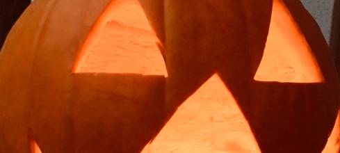 Ein Kürbis mit einer geschnitzten und beleuchteten Grimasse.