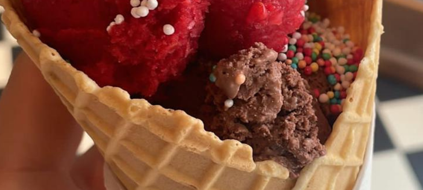 Eine rote Eiskugel mit Streuseln in einem Hörnchen.