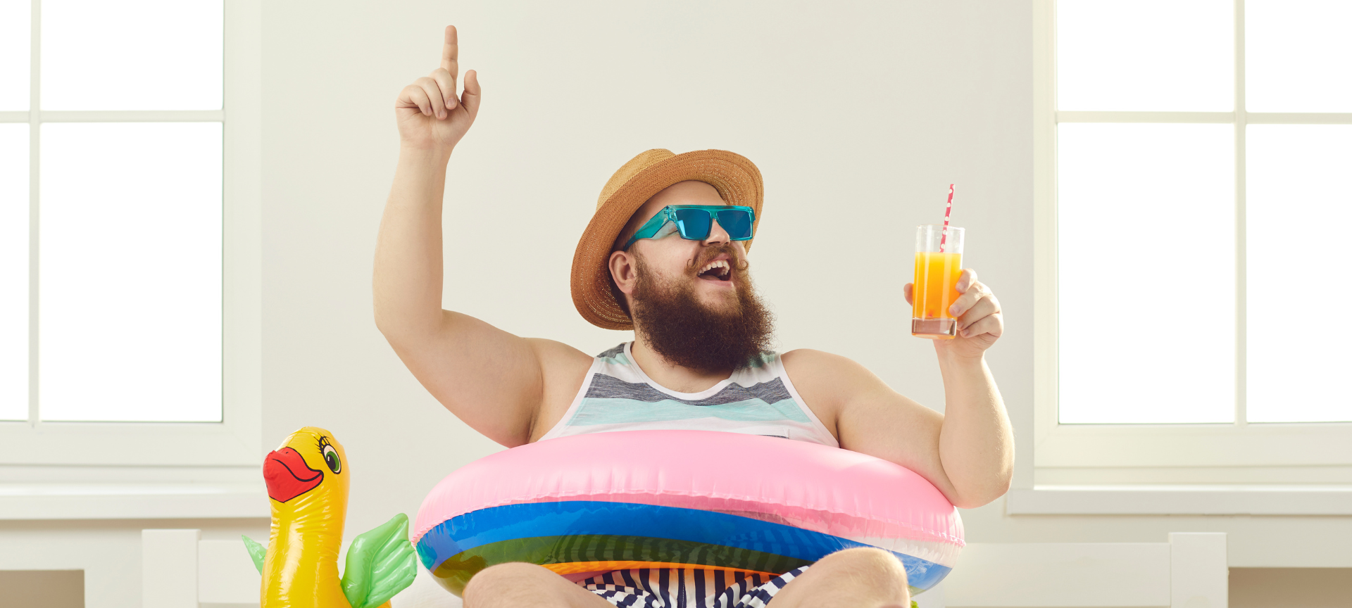 Urlaubsstimmung: Ein Mann sitzt auf einer Luftmatratze und hat einen Cocktail in der Hand.