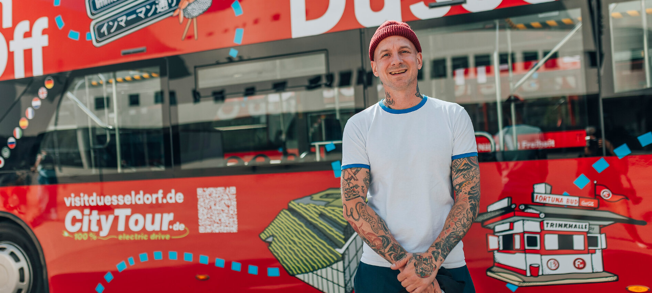 Die neuen elektrischen Hop-on-hop-off-Busse. Davor steht ein Mann mit T-Shirt und Mütze.